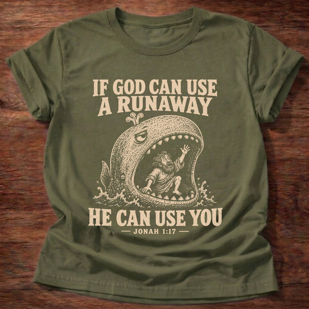 Military Green t-shirt printed with a whale swallowing a runaway figure and 'If God can use a runaway, He can use you.' Jonah 1:17 faith based gift