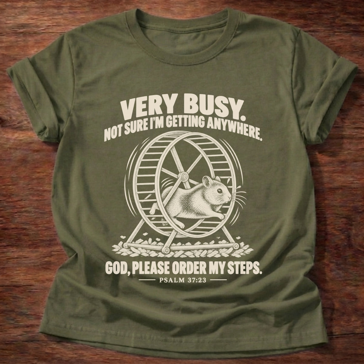 Military Green t-shirt printed with a squirrel running on a wheel graphic and 'Very busy. Not sure I'm getting anywhere. God, please order my steps.' Psalm 37:23 faith based gift
