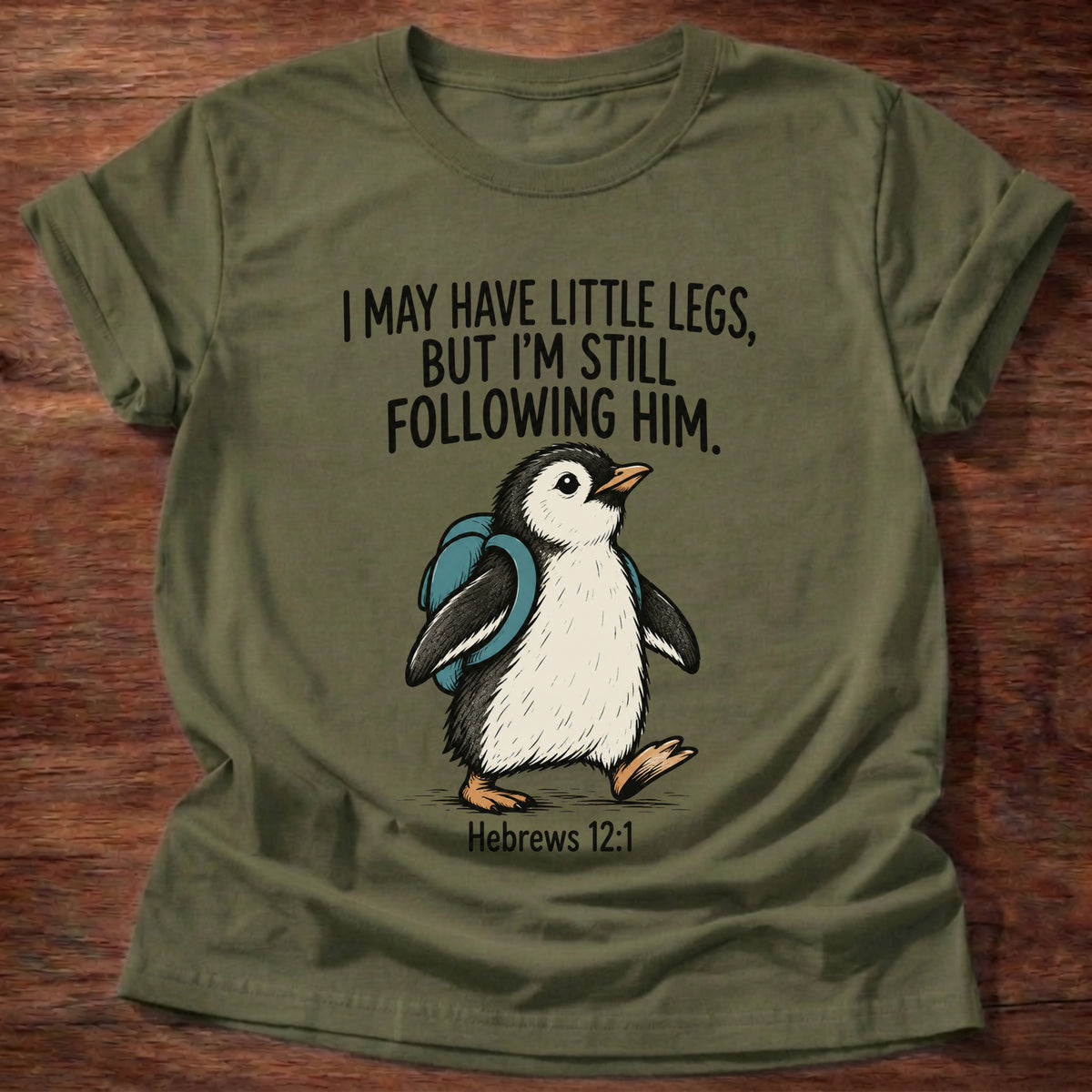 Military Green t-shirt printed with a penguin graphic and 'I may have little legs, but I'm still following Him.' Hebrews 12:1 faith based gift