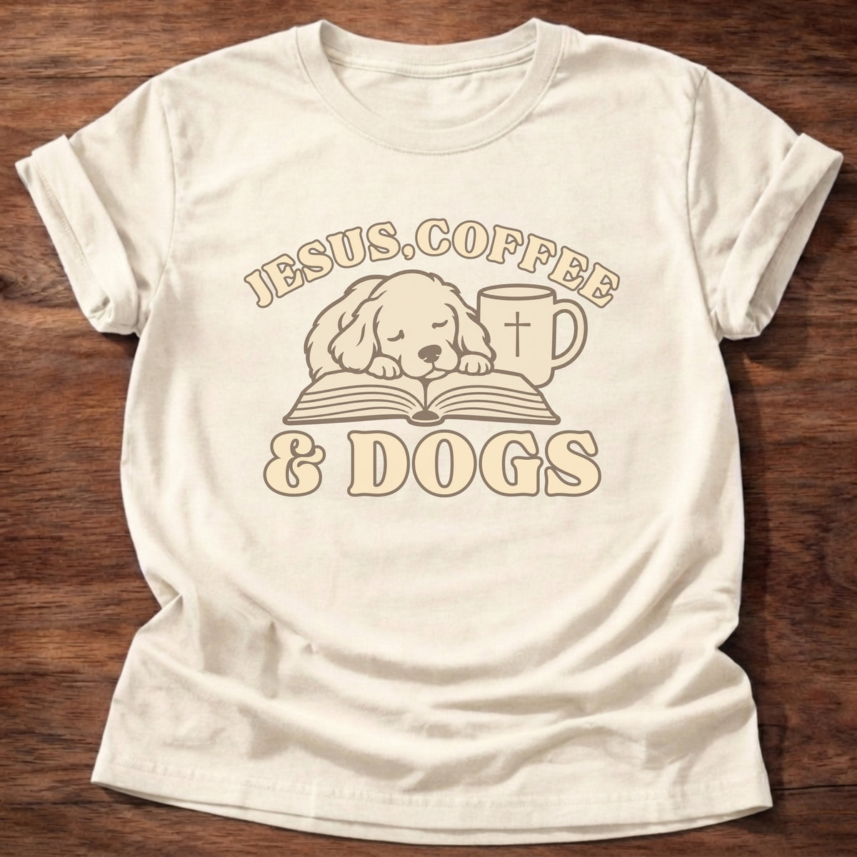Natural t-shirt printed with a sleepy puppy resting on an open Bible beside a coffee mug with a cross and “Jesus, Coffee & Dogs” Christian shirt