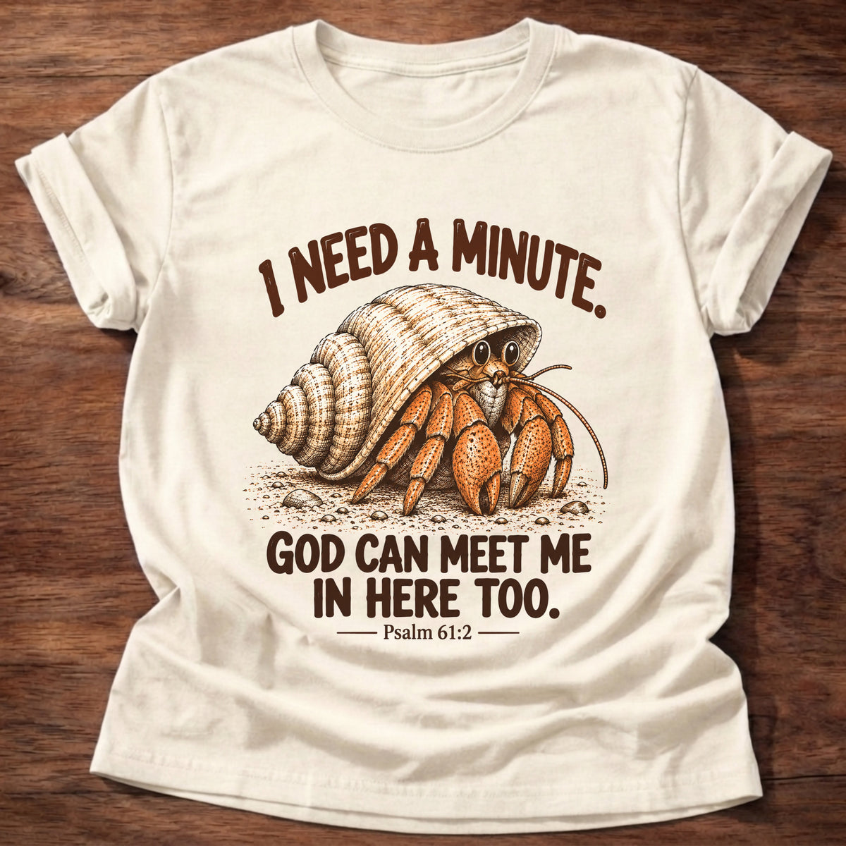 Natural t-shirt printed with a hermit crab peeking out of its spiral shell graphic and “I need a minute. God can meet me in here too.” Psalm 61:2 faith based gift