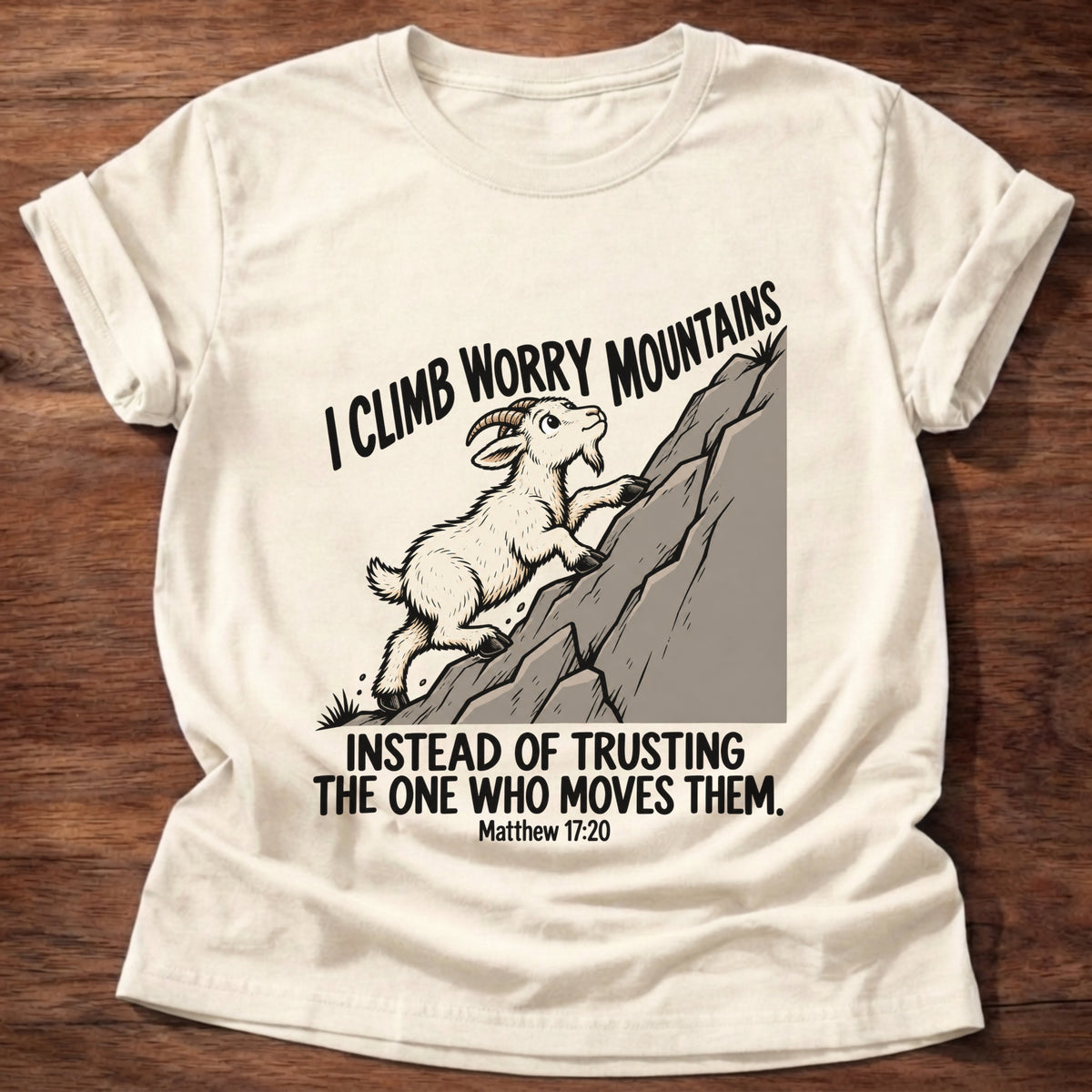 Natural t-shirt printed with a goat climbing a mountain graphic and 'I climb worry mountains instead of trusting the One who moves them.' Matthew 17:20 faith based gift