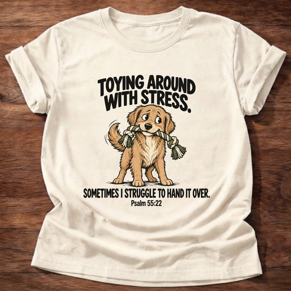 Natural t-shirt printed with a dog tugging a rope toy graphic and 'Toying around with stress. Sometimes I struggle to hand it over.' Psalm 55:22 faith based gift