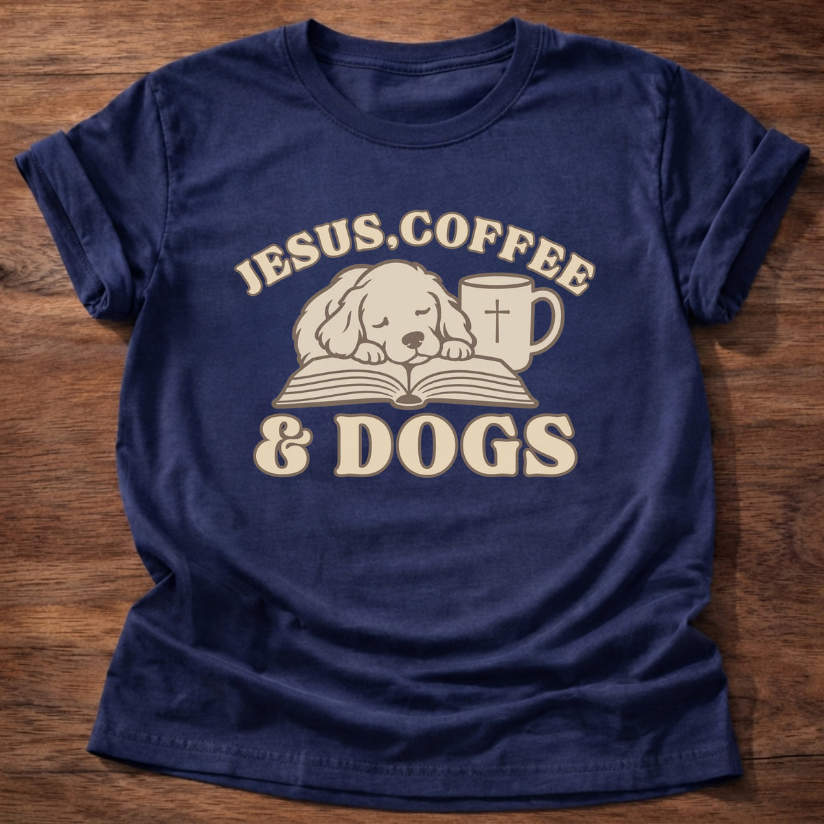 Navy t-shirt printed with a sleepy puppy resting on an open Bible beside a coffee mug with a cross and “Jesus, Coffee & Dogs” Christian shirt