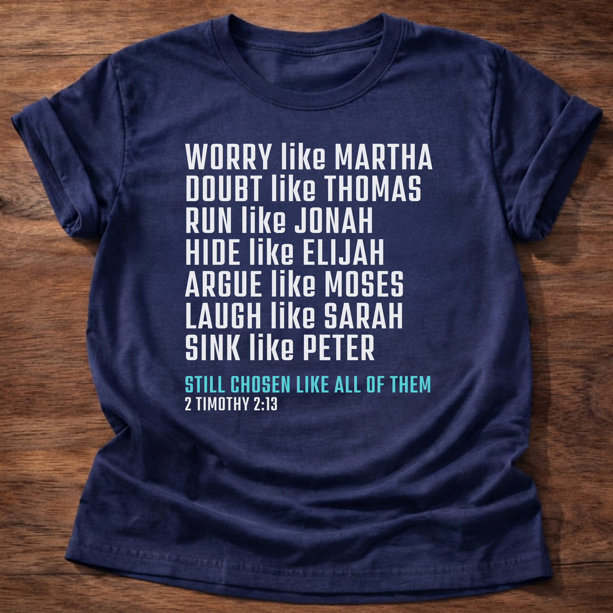 Navy t-shirt printed with bold stacked typography listing Bible characters graphic and “Worry like Martha. Doubt like Thomas. Sink like Peter. Still chosen like all of them.” 2 Timothy 2:13 Christian shirt