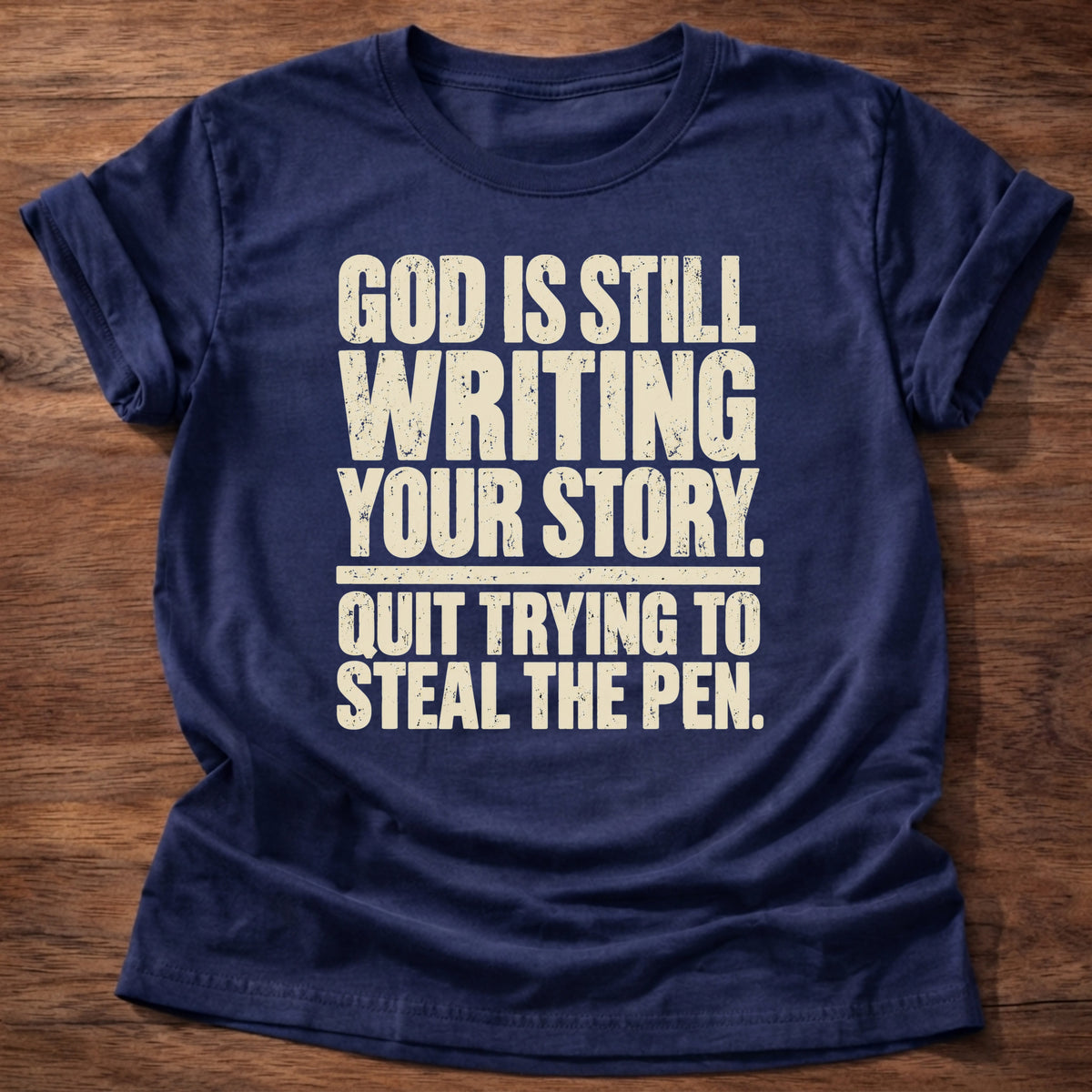 Navy t-shirt printed with bold stacked typography graphic and “God is still writing your story. Quit trying to steal the pen.” Philippians 1:6 Christian shirt