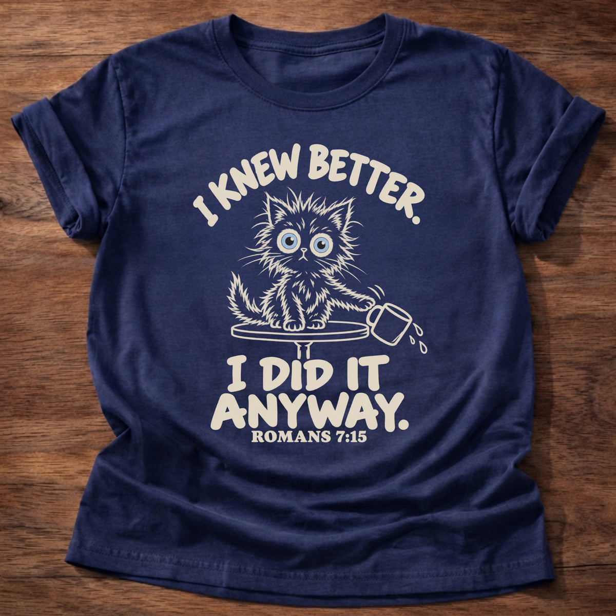Navy t-shirt printed with a scruffy kitten knocking a cup off a table and “I knew better. I did it anyway.” Romans 7:15 Christian shirt