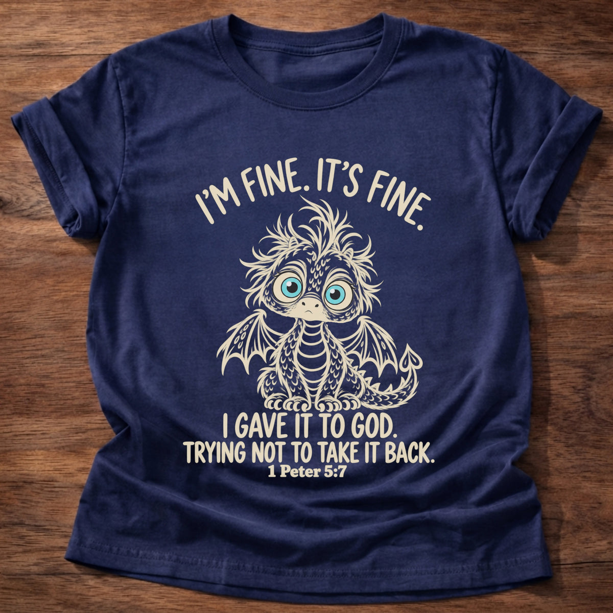 Navy t-shirt printed with a wide-eyed, frazzled baby dragon graphic and “I'm fine. It's fine. I gave it to God. Trying not to take it back.” 1 Peter 5:7 Christian shirt