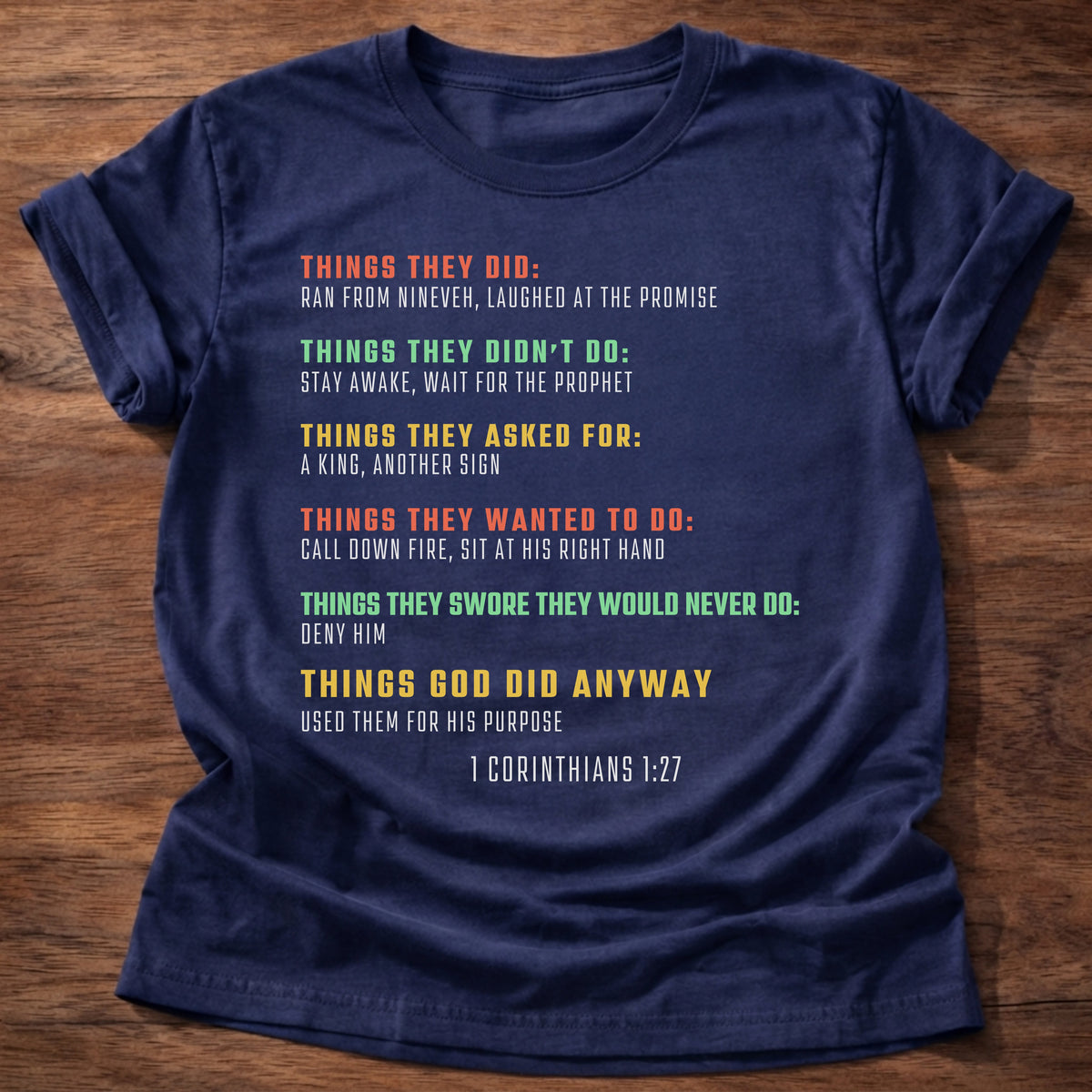 Navy t-shirt printed with bold colorful typography listing what Bible heroes did graphic and “Things they did. Things God did anyway.” 1 Corinthians 1:27 Christian shirt