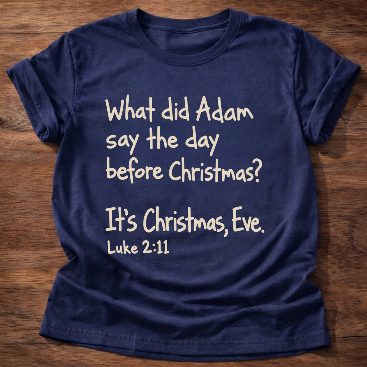 Navy t-shirt printed with a simple hand-lettered Bible joke graphic and “What did Adam say the day before Christmas? It's Christmas, Eve.” Luke 2:11 Christian shirt