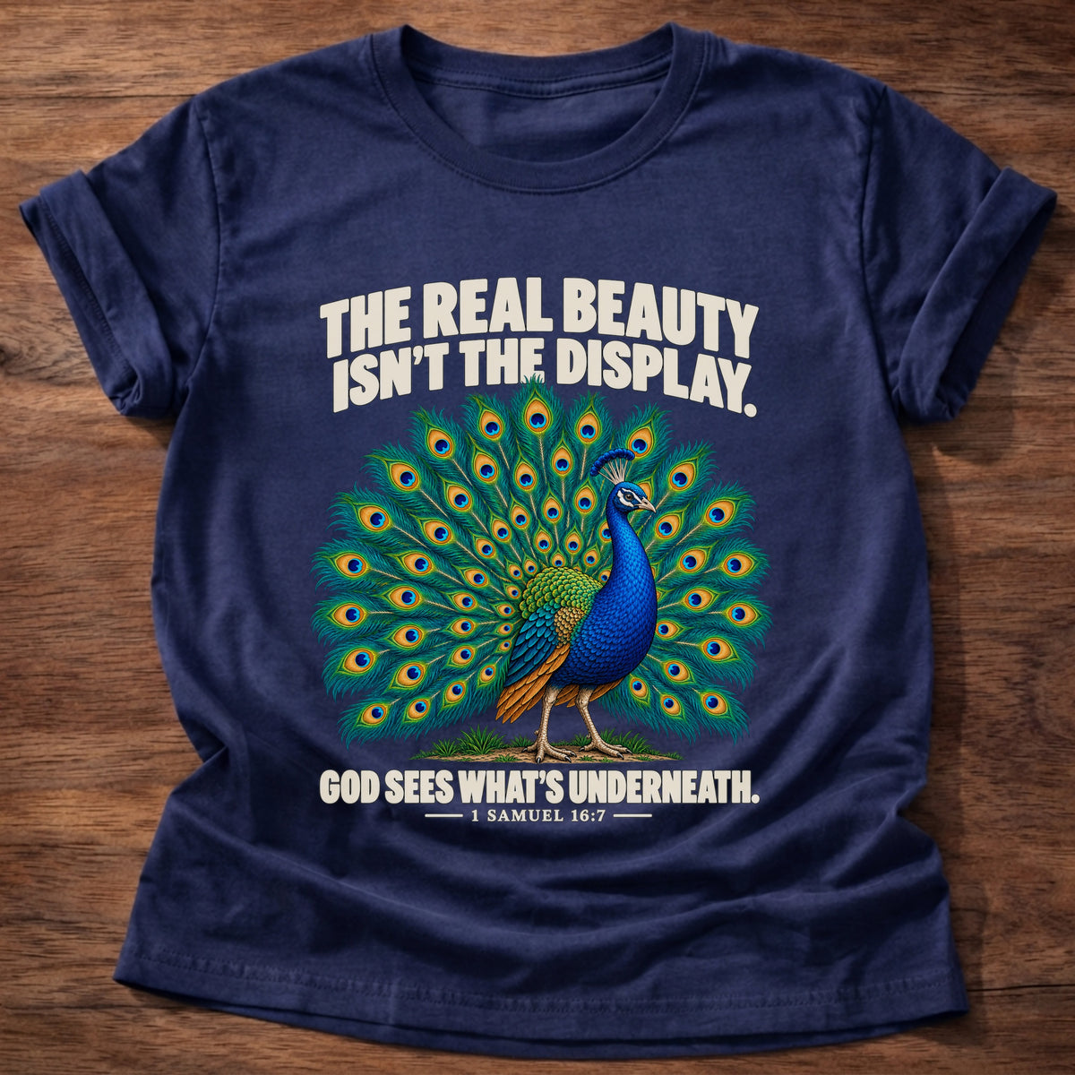 Navy t-shirt printed with a peacock with feathers in full display graphic and 'The real beauty isn't the display. God sees what's underneath.' 1 Samuel 16:7 faith based gift