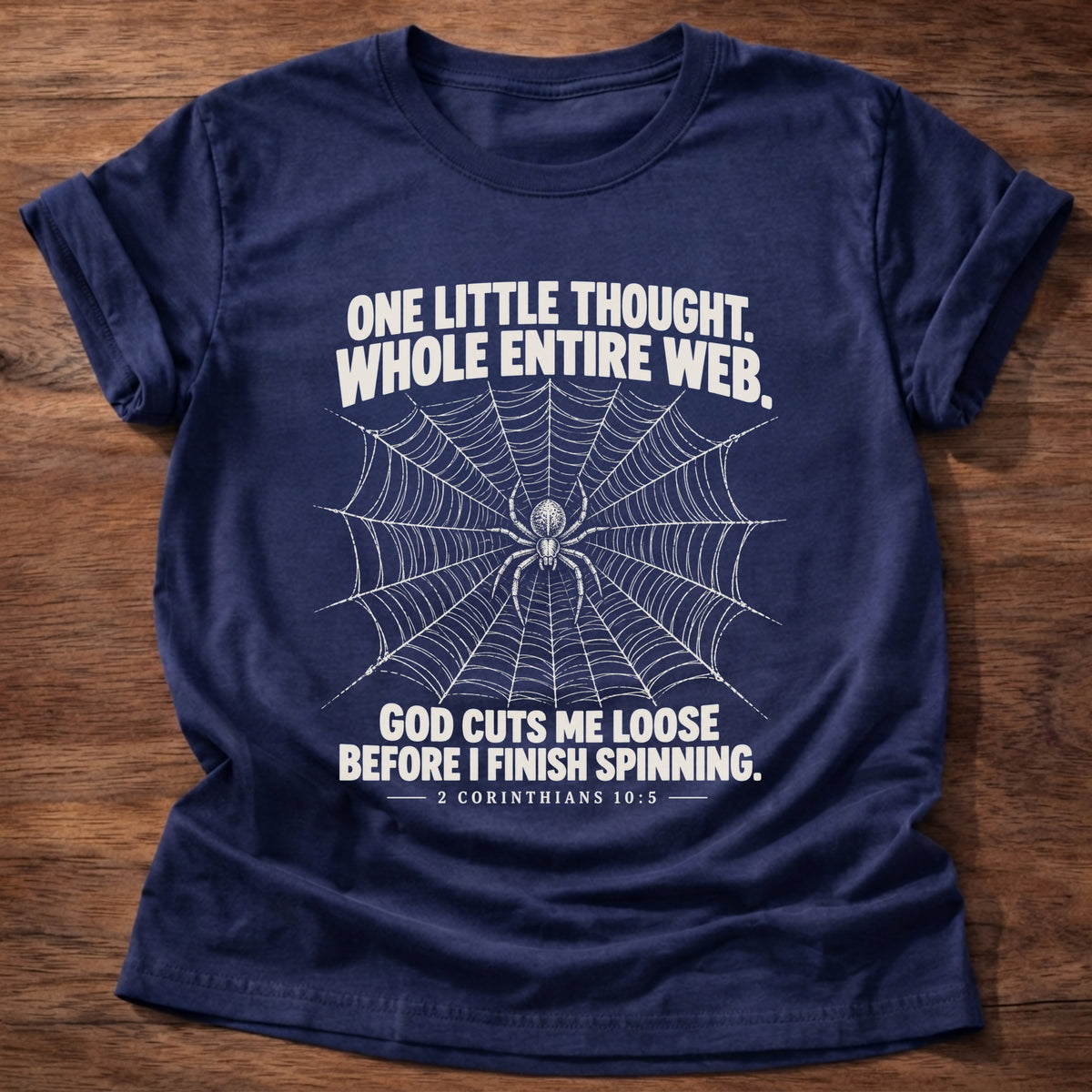 Navy t-shirt printed with a spider at the center of its web graphic and 'One little thought. Whole entire web. God cuts me loose before I finish spinning.' 2 Corinthians 10:5 faith based gift