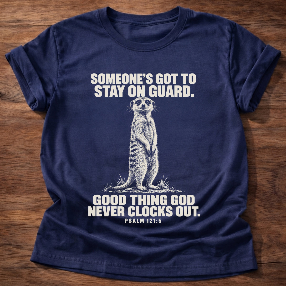 Navy t-shirt printed with a meerkat standing guard on lookout graphic and 'Someone's got to stay on guard. Good thing God never clocks out.' Psalm 121:5 faith based gift