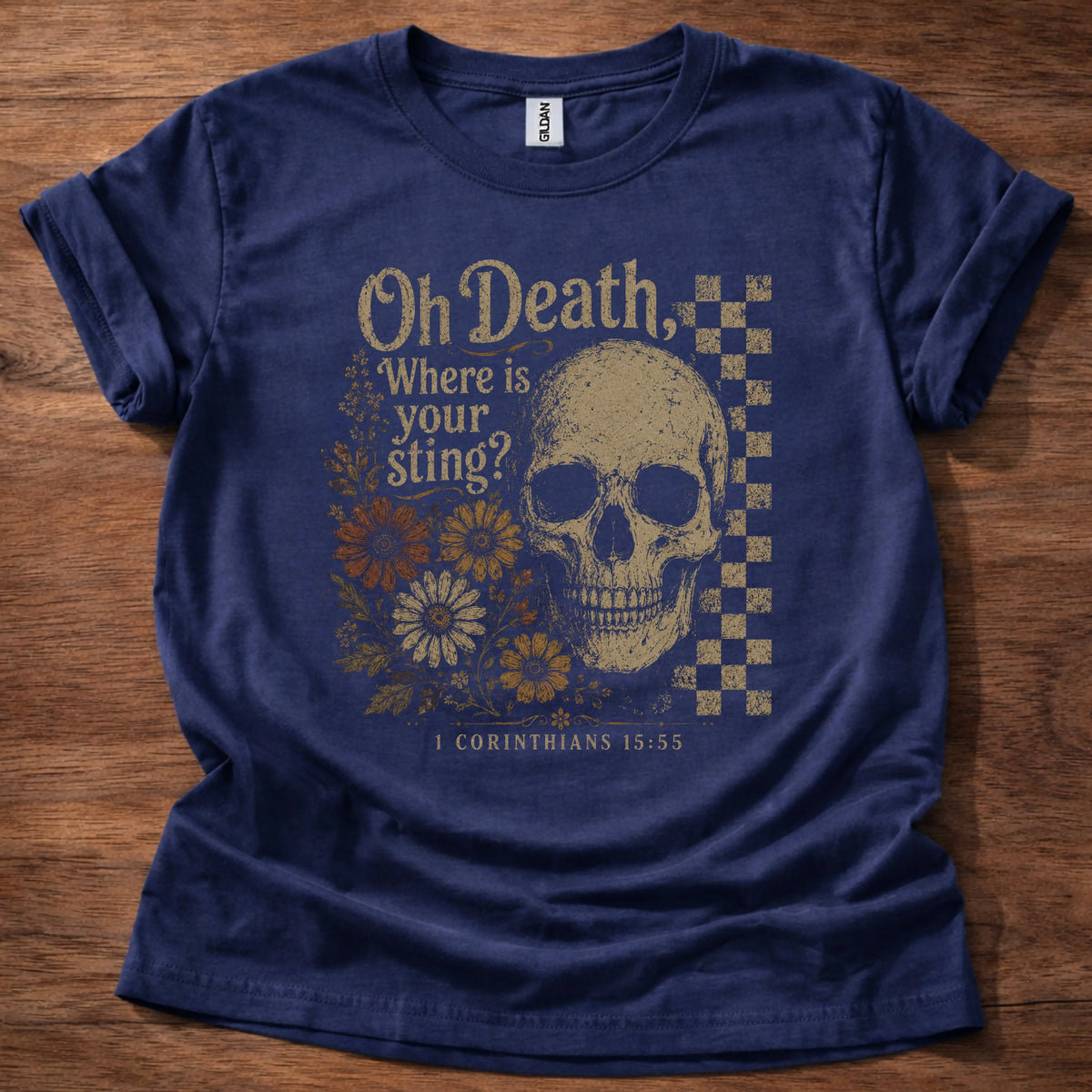 Navy t-shirt with a large gold skull, checkerboard accent panel, and a floral cluster beneath text reading Oh Death, Where Is Your Sting, 1 Corinthians 15:55
