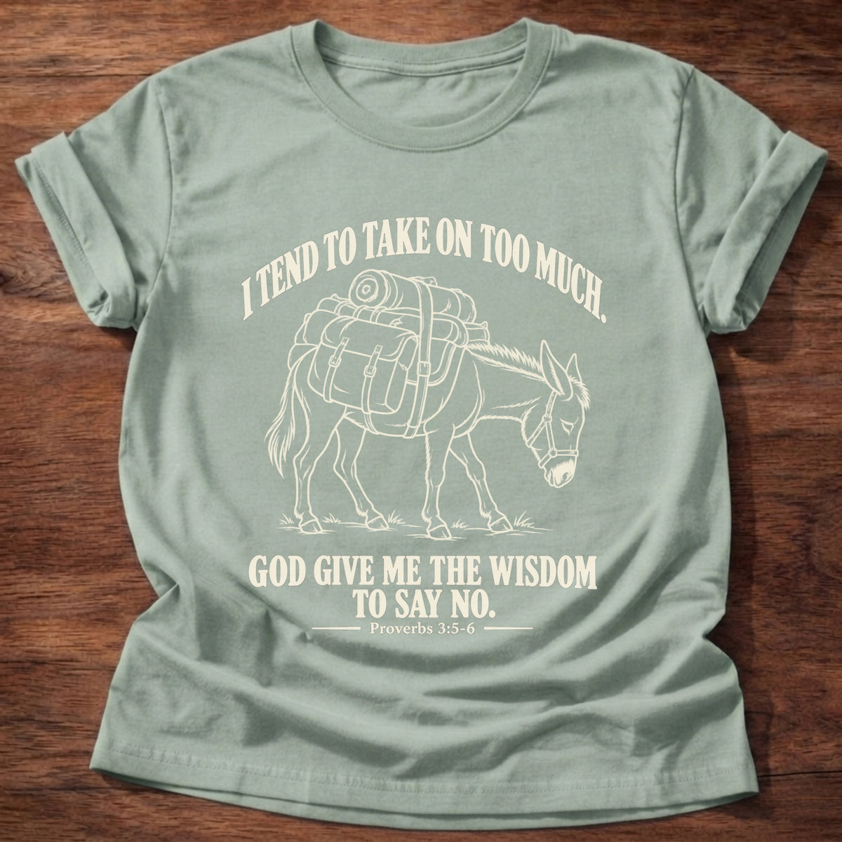 Sage t-shirt printed with a pack donkey weighed down with overstuffed bags and bundles graphic and “I tend to take on too much. God give me the wisdom to say no.” Proverbs 3:5-6 faith based gift