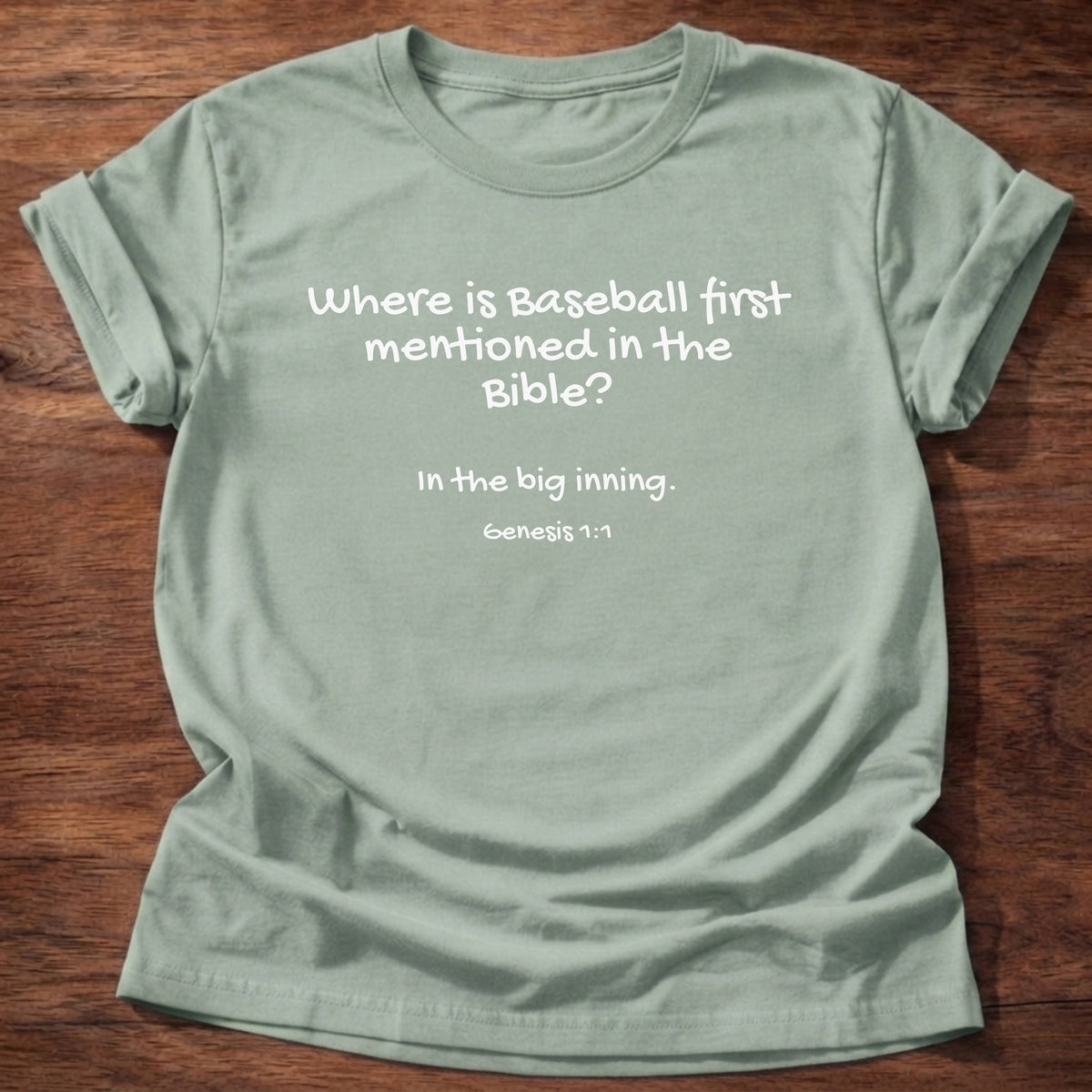 Sage t-shirt printed with a simple hand-lettered Bible joke graphic and “Where is baseball first mentioned in the Bible? In the big inning.” Genesis 1:1 Christian shirt