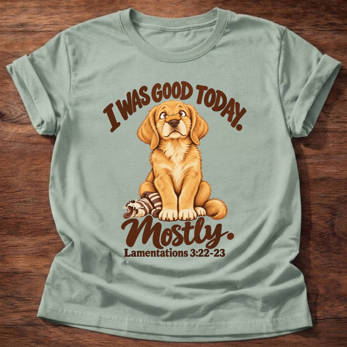 Sage t-shirt printed with a golden retriever puppy sitting beside a chewed-up toy and “I was good today. Mostly.” Lamentations 3:22-23 Christian shirt
