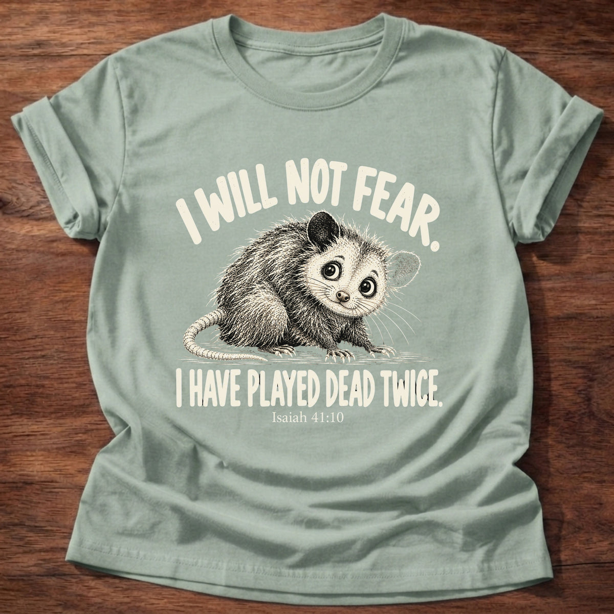 Sage t-shirt printed with a wide-eyed opossum graphic and “I will not fear. I have played dead twice.” Isaiah 41:10 Christian shirt