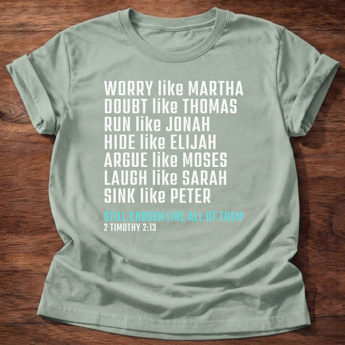 Sage t-shirt printed with bold stacked typography listing Bible characters graphic and “Worry like Martha. Doubt like Thomas. Sink like Peter. Still chosen like all of them.” 2 Timothy 2:13 Christian shirt