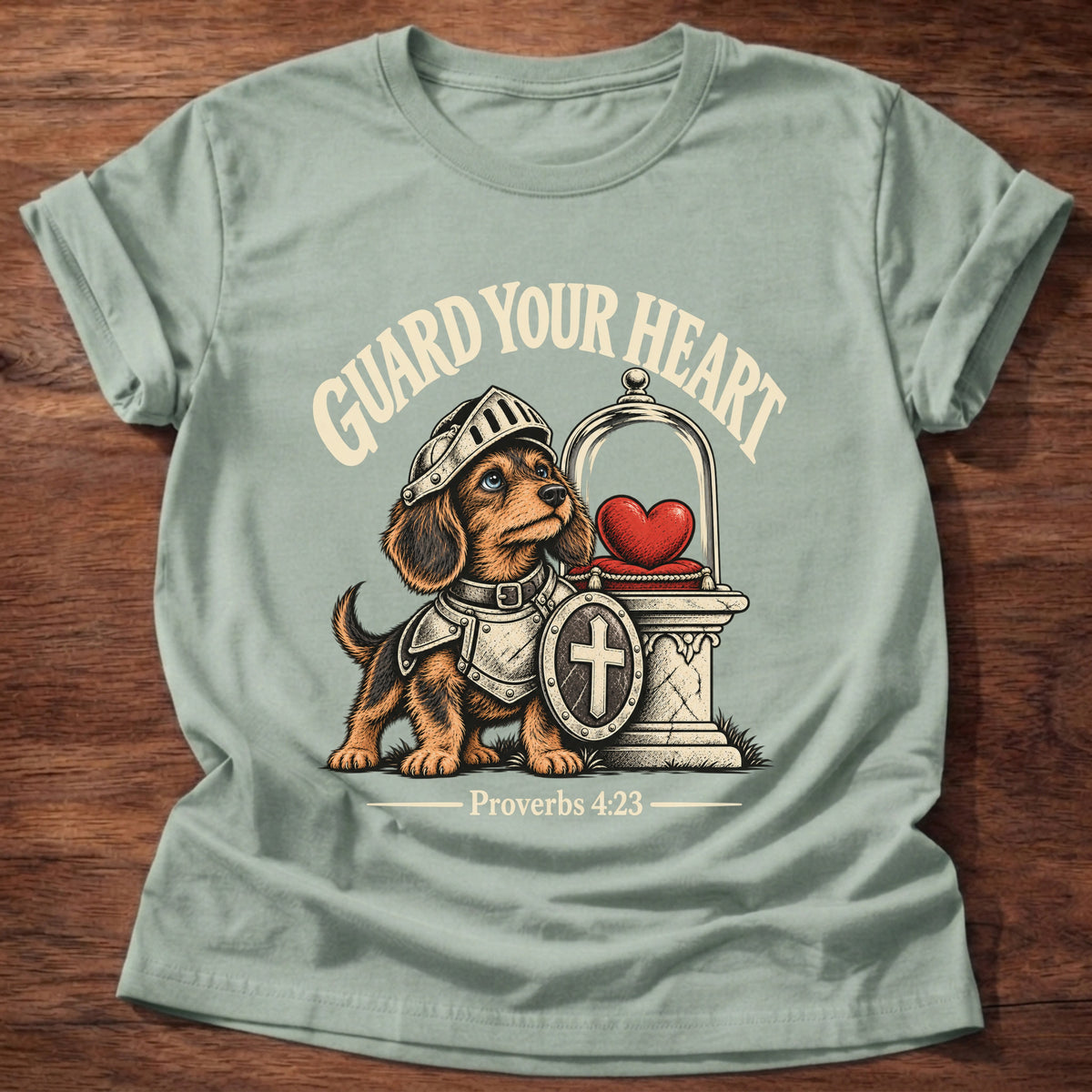 Sage t-shirt printed with a brave knight dachshund in armor guarding a glowing heart graphic and “Guard your heart.” Proverbs 4:23 Christian shirt