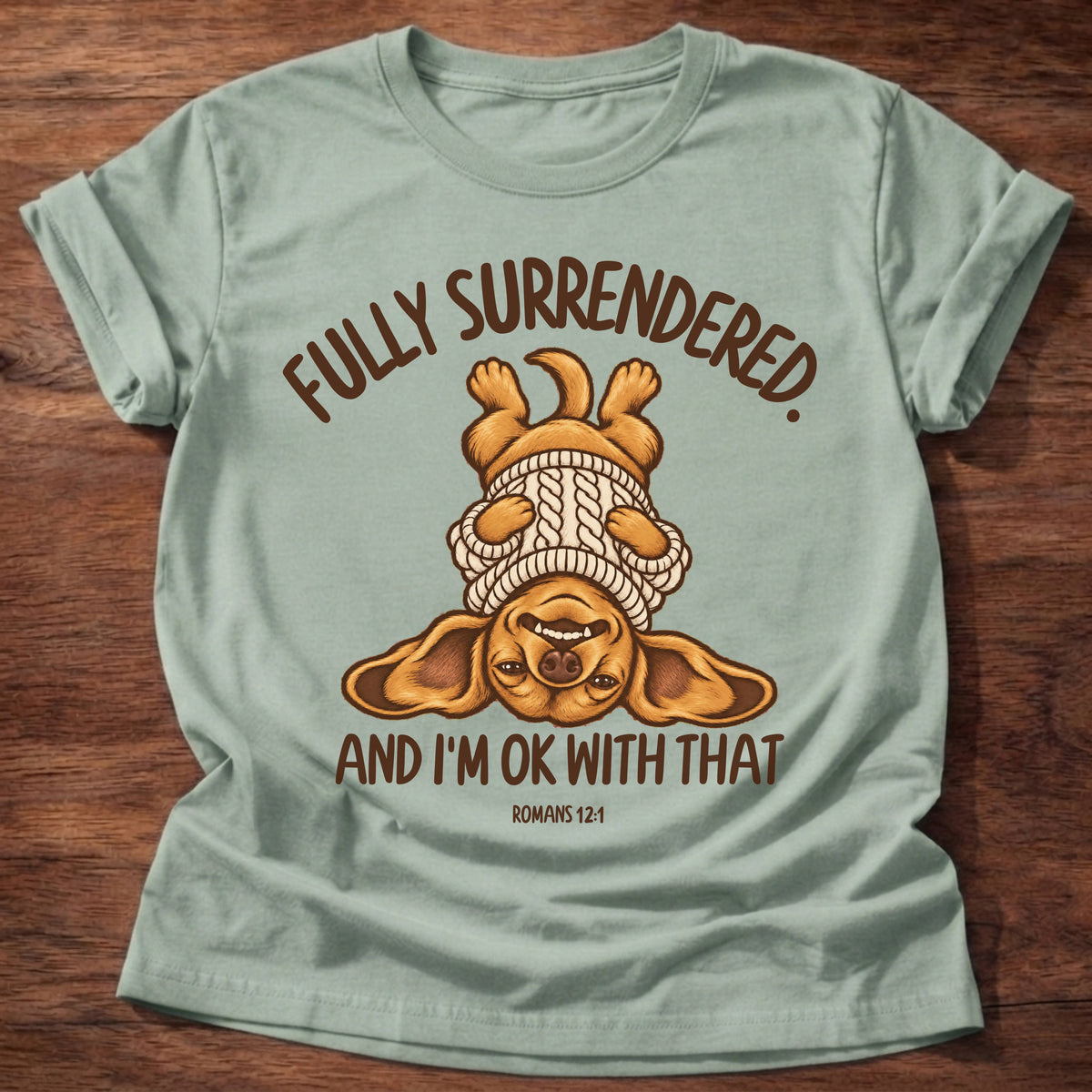 Sage t-shirt printed with an upside-down puppy in a cozy sweater and “Fully surrendered. And I'm OK with that.” Romans 12:1 Christian shirt