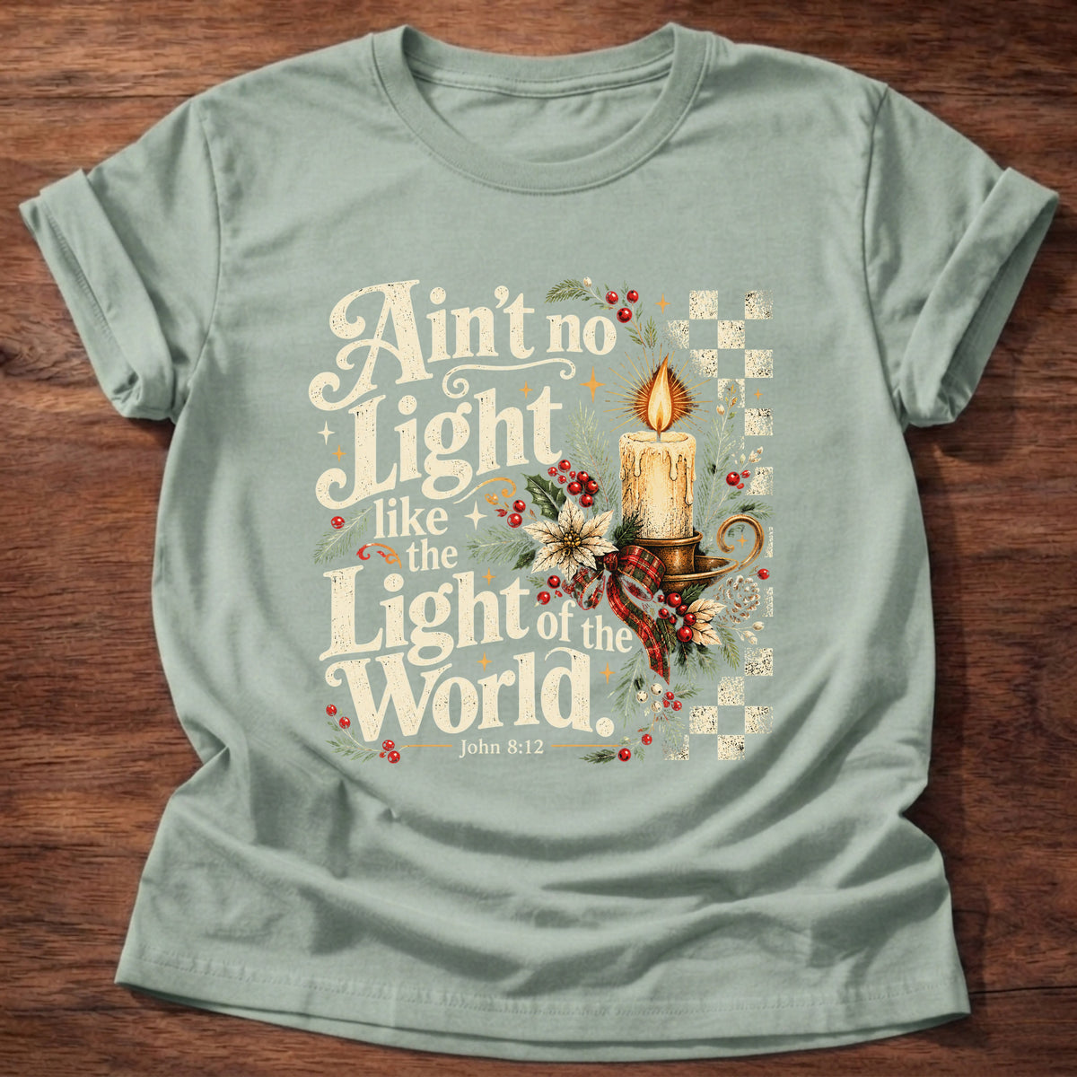 Sage t-shirt printed with a retro glowing candle with poinsettias and checkerboard graphic and “Ain't no light like the Light of the World.” John 8:12 Christian shirt