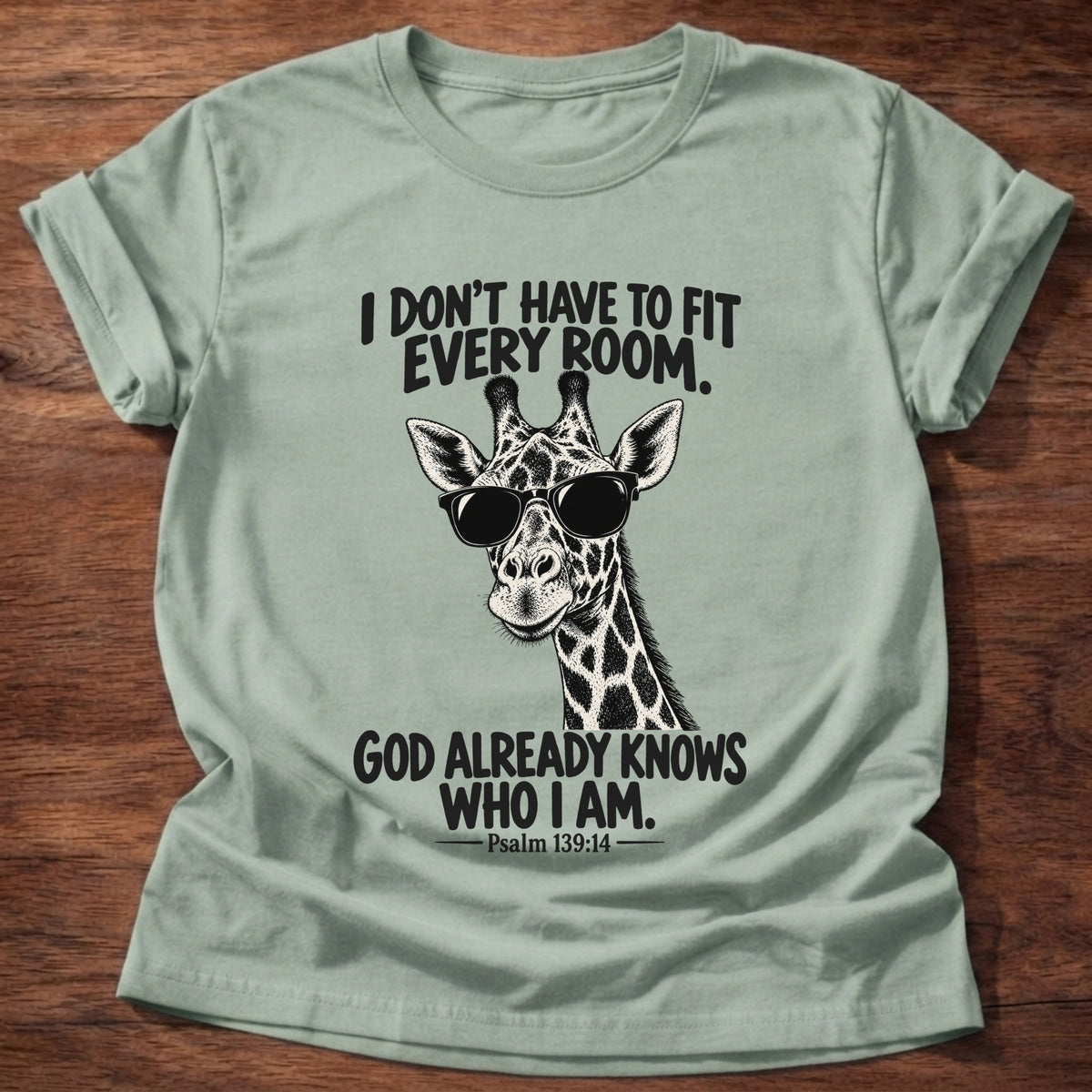 Sage t-shirt printed with a giraffe wearing dark sunglasses graphic and “I don't have to fit every room. God already knows who I am.” Psalm 139:14 faith based gift