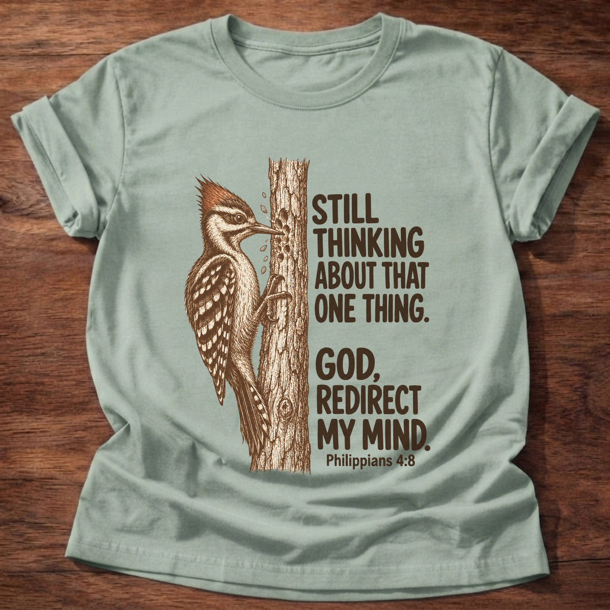 Sage t-shirt printed with a woodpecker pecking at a tree trunk graphic and “Still thinking about that one thing. God, redirect my mind.” Philippians 4:8 faith based gift