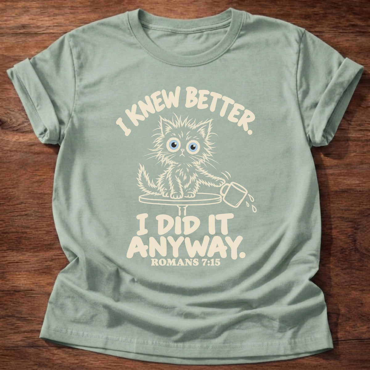 Sage t-shirt printed with a scruffy kitten knocking a cup off a table and “I knew better. I did it anyway.” Romans 7:15 Christian shirt
