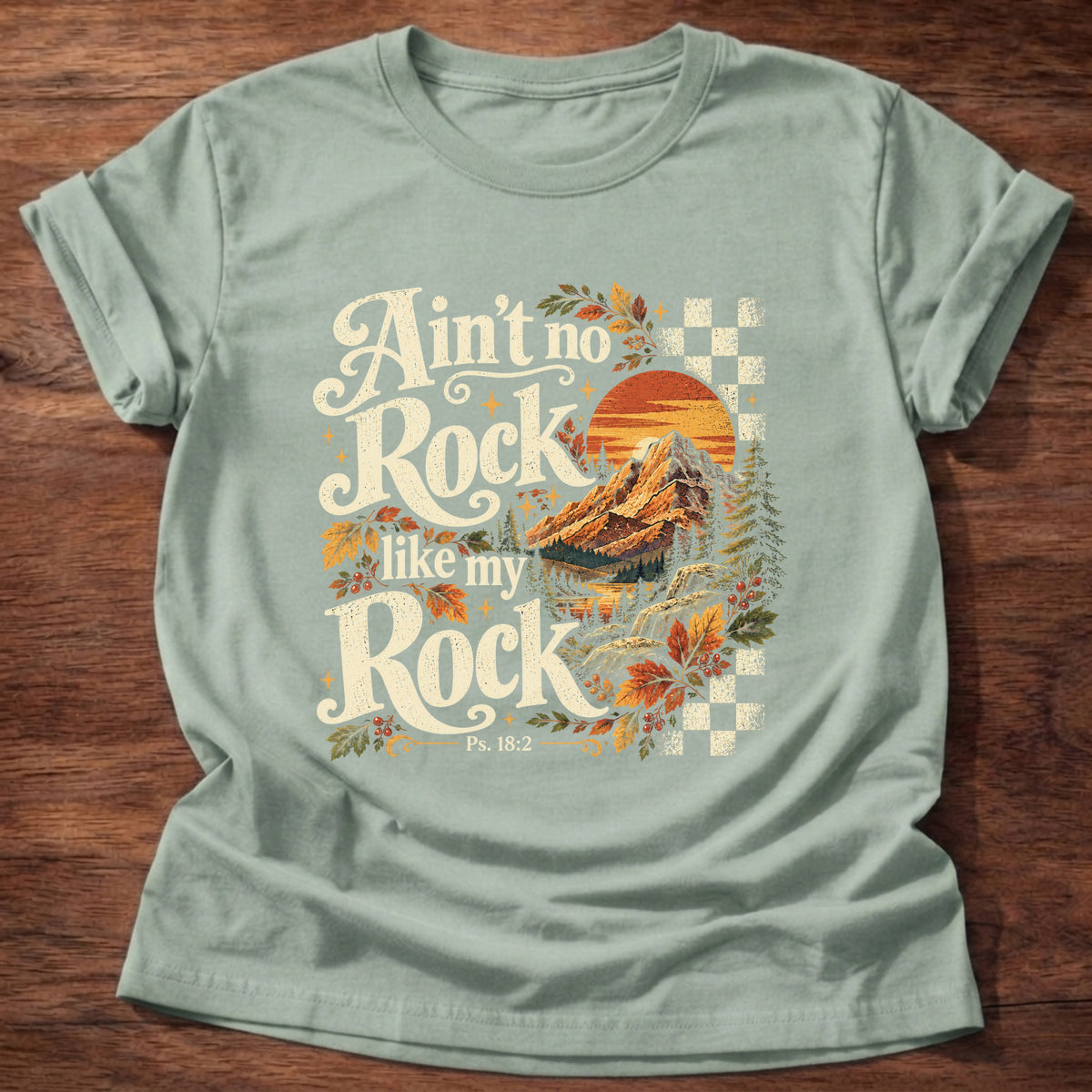 Sage t-shirt printed with a retro mountain sunset with autumn leaves and checkerboard graphic and “Ain't no Rock like my Rock.” Psalm 18:2 Christian shirt