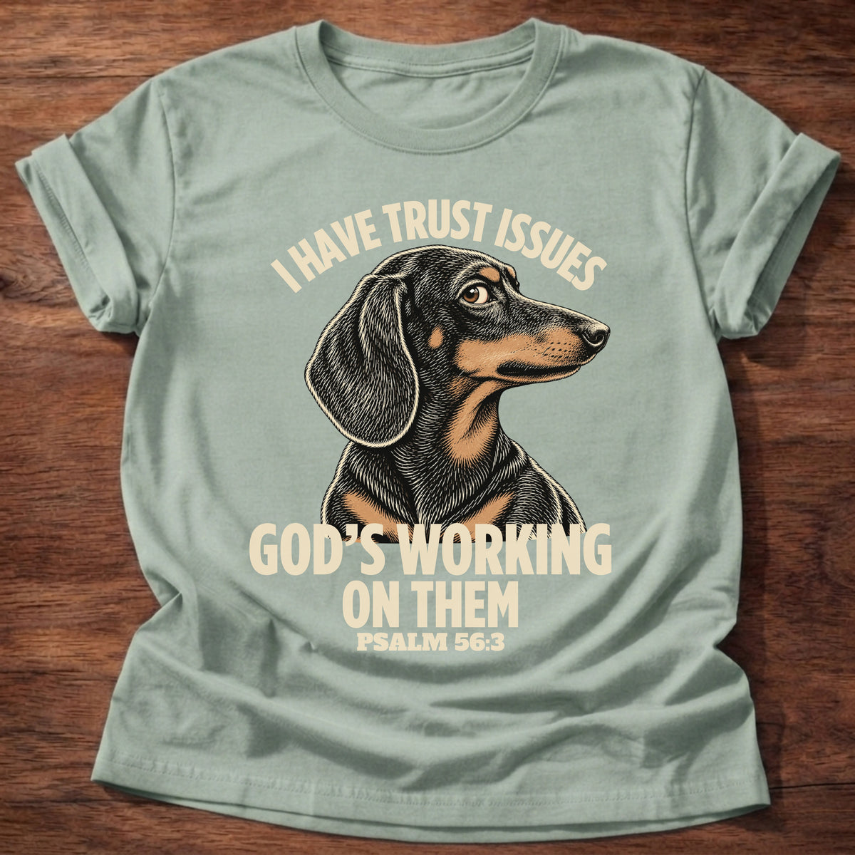 Sage t-shirt printed with a wary dachshund puppy and “I have trust issues. God's working on them.” Psalm 56:3 Christian shirt