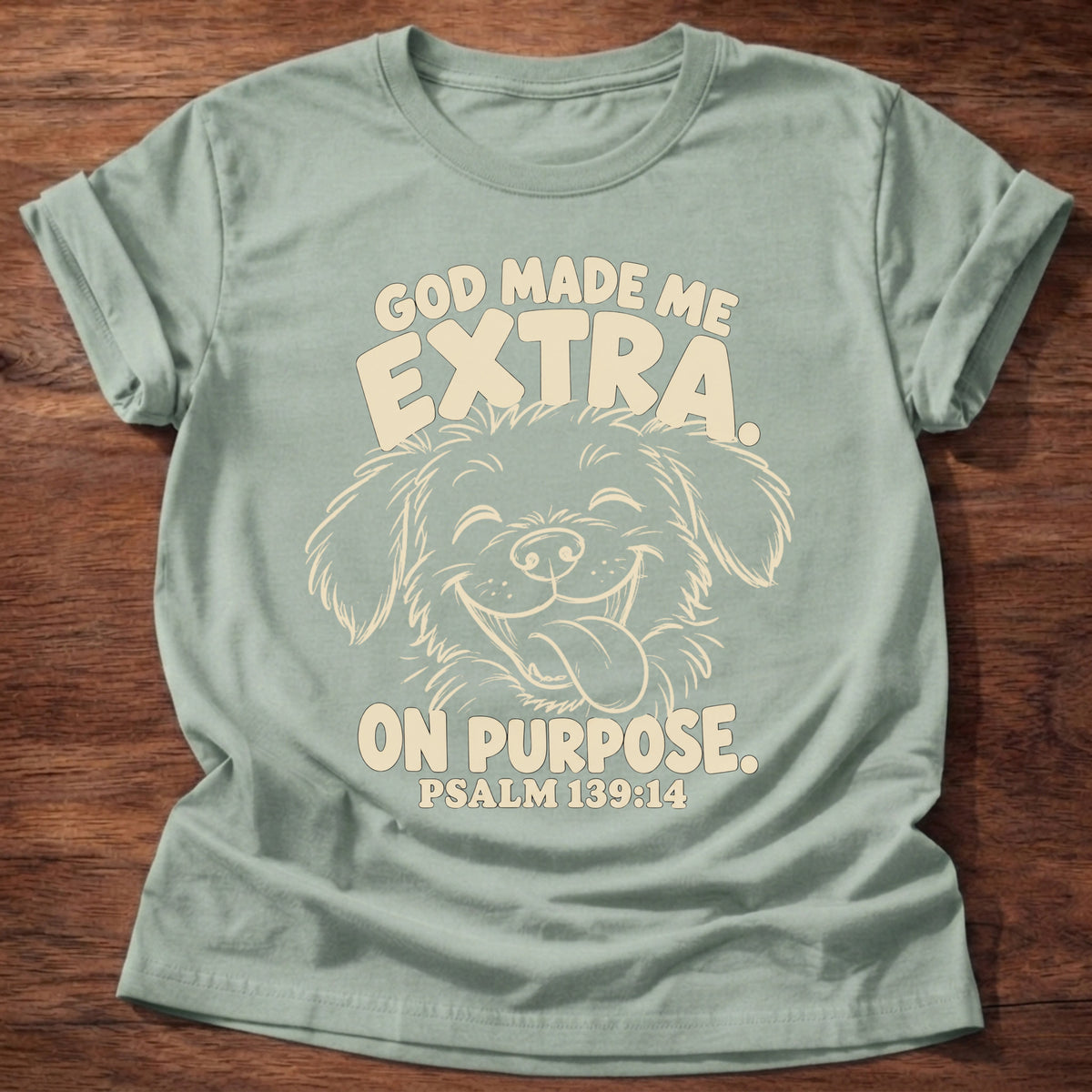 Sage t-shirt printed with a fluffy, happy dog with its tongue out and “God made me extra. On purpose.” Psalm 139:14 Christian shirt