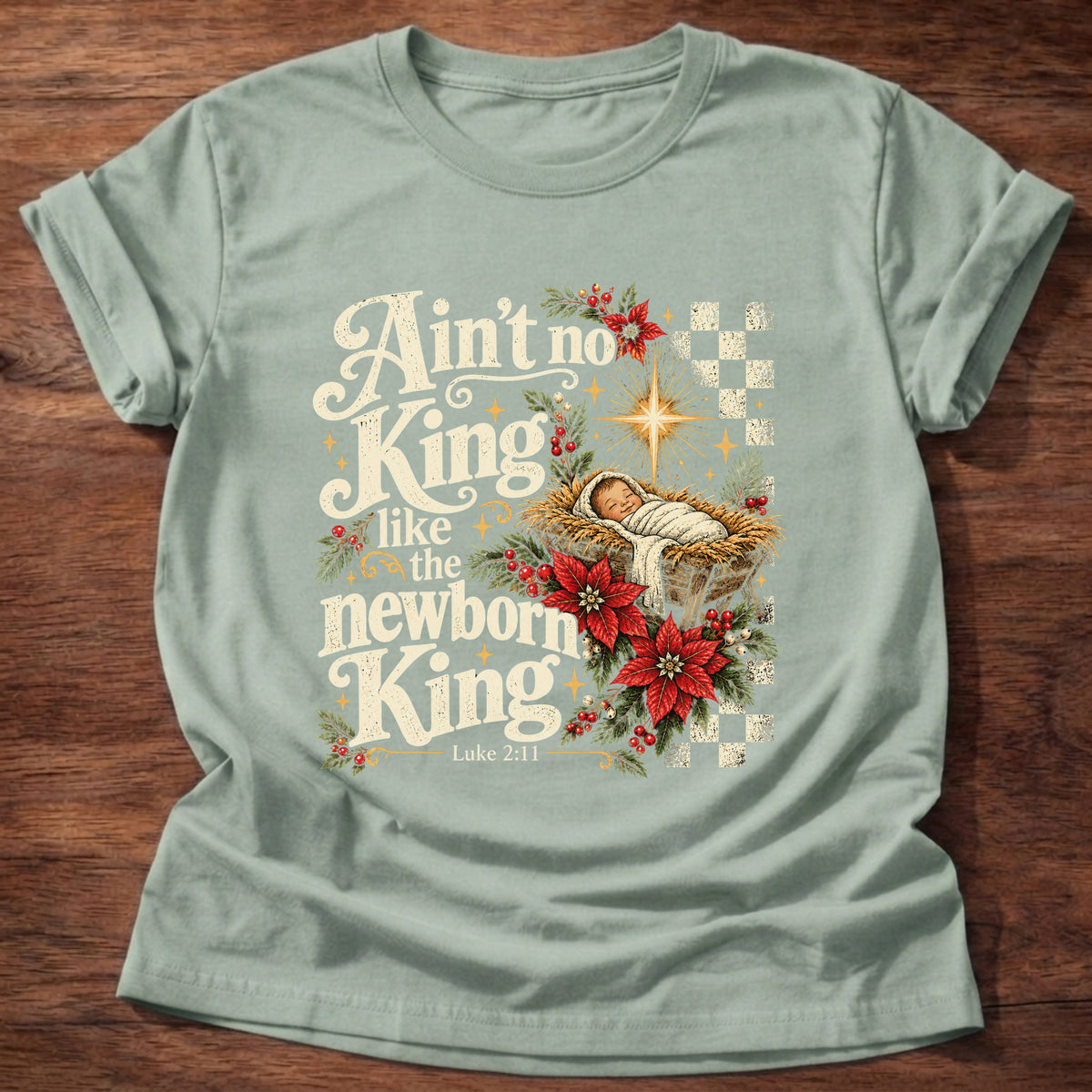 Sage t-shirt printed with a retro manger scene with a star, poinsettias and checkerboard graphic and “Ain't no King like the newborn King.” Luke 2:11 Christian shirt