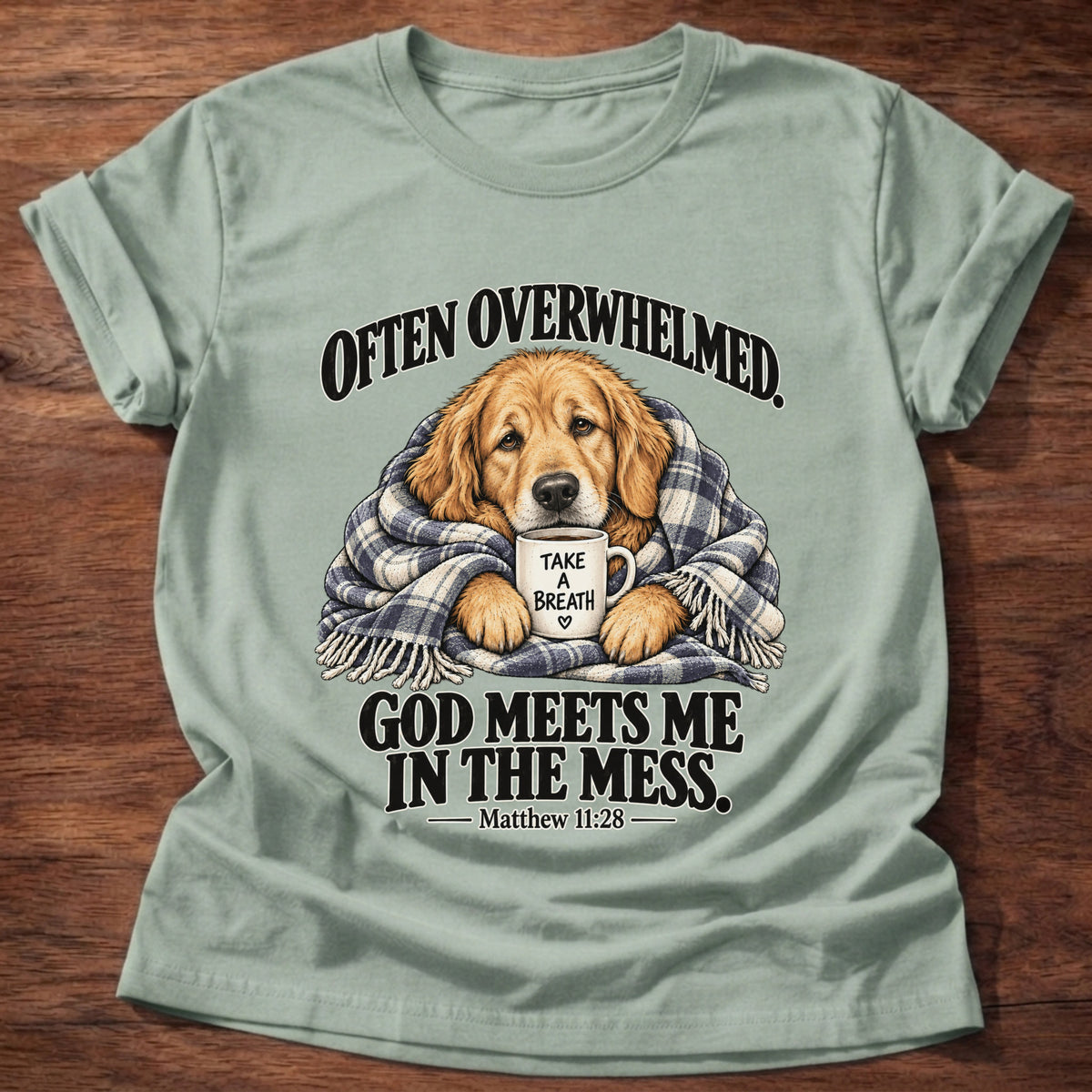 Sage t-shirt printed with a golden retriever wrapped in a plaid blanket holding a 'Take a Breath' mug graphic and “Often overwhelmed. God meets me in the mess.” Matthew 11:28 faith based gift
