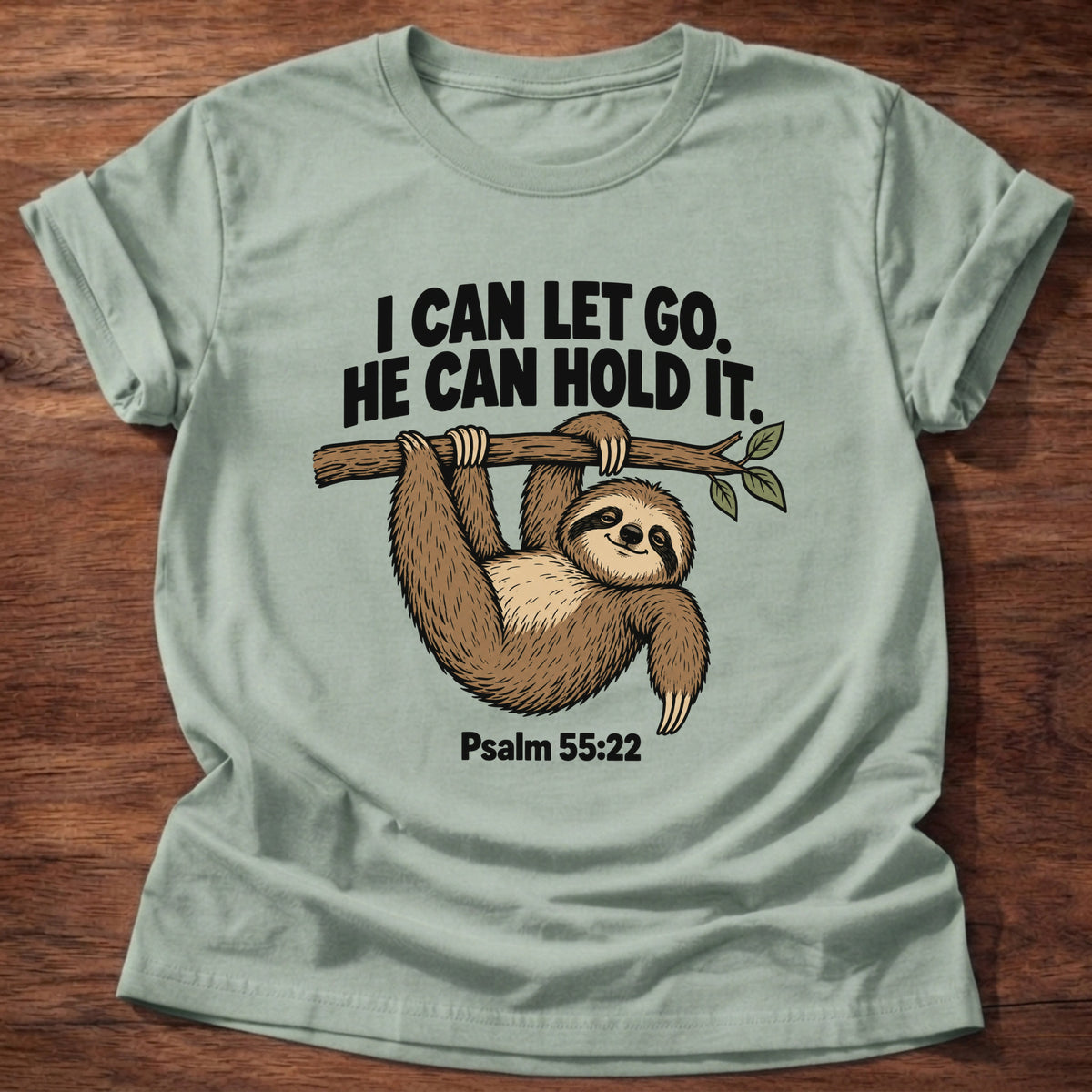 Sage t-shirt printed with a sloth hanging from a branch graphic and 'I can let go. He can hold it.' Psalm 55:22 faith based gift