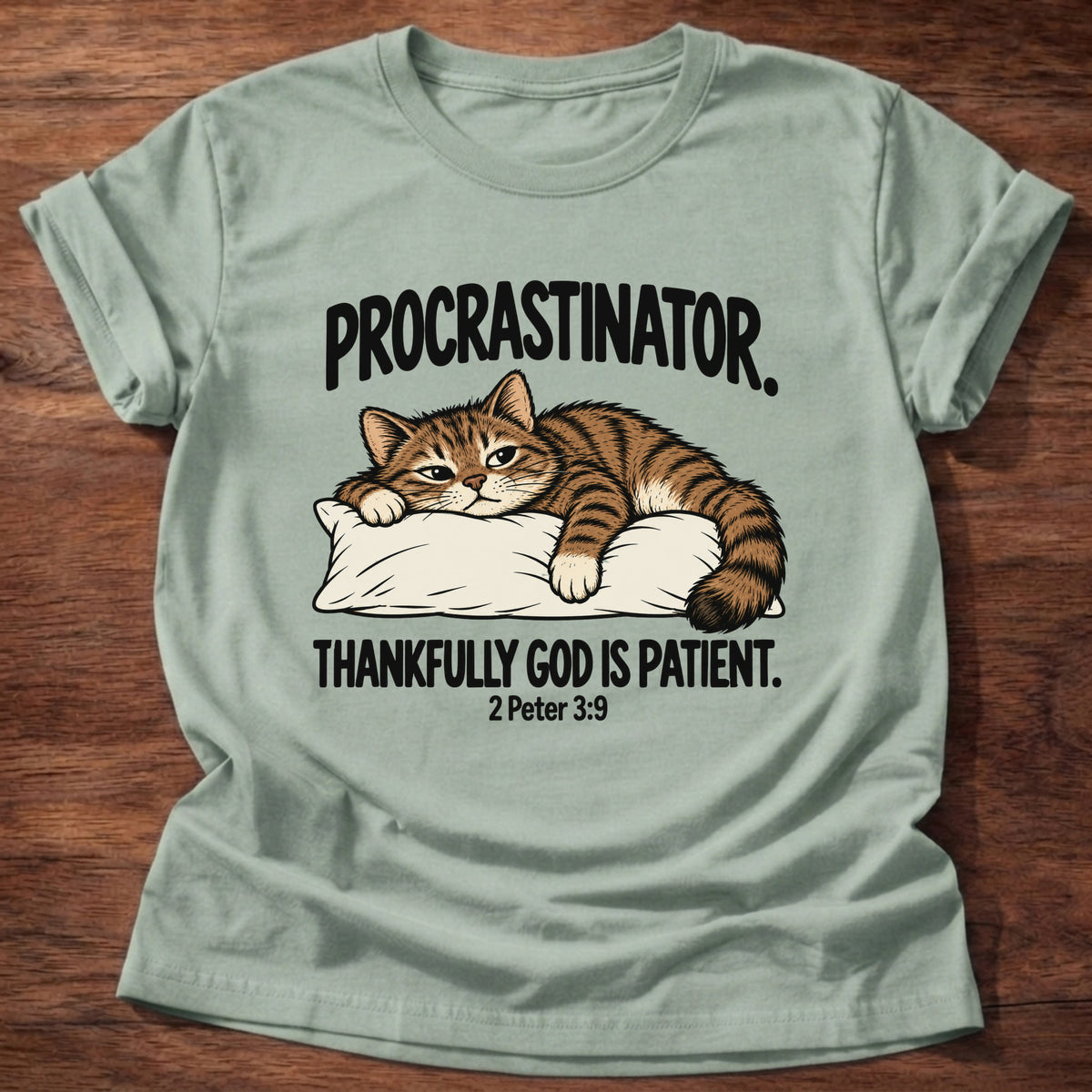 Sage t-shirt printed with a cat sleeping on a pillow graphic and 'Procrastinator. Thankfully God is patient.' 2 Peter 3:9 faith based gift