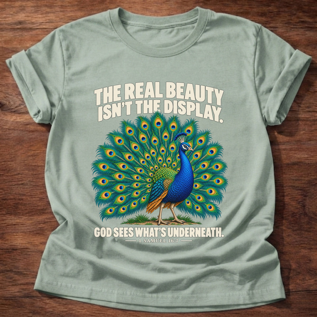 Sage t-shirt printed with a peacock with feathers in full display graphic and 'The real beauty isn't the display. God sees what's underneath.' 1 Samuel 16:7 faith based gift