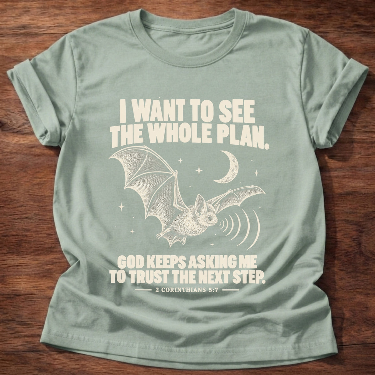 Sage t-shirt printed with a bat flying under a night sky graphic and 'I want to see the whole plan. God keeps asking me to trust the next step.' 2 Corinthians 5:7 faith based gift