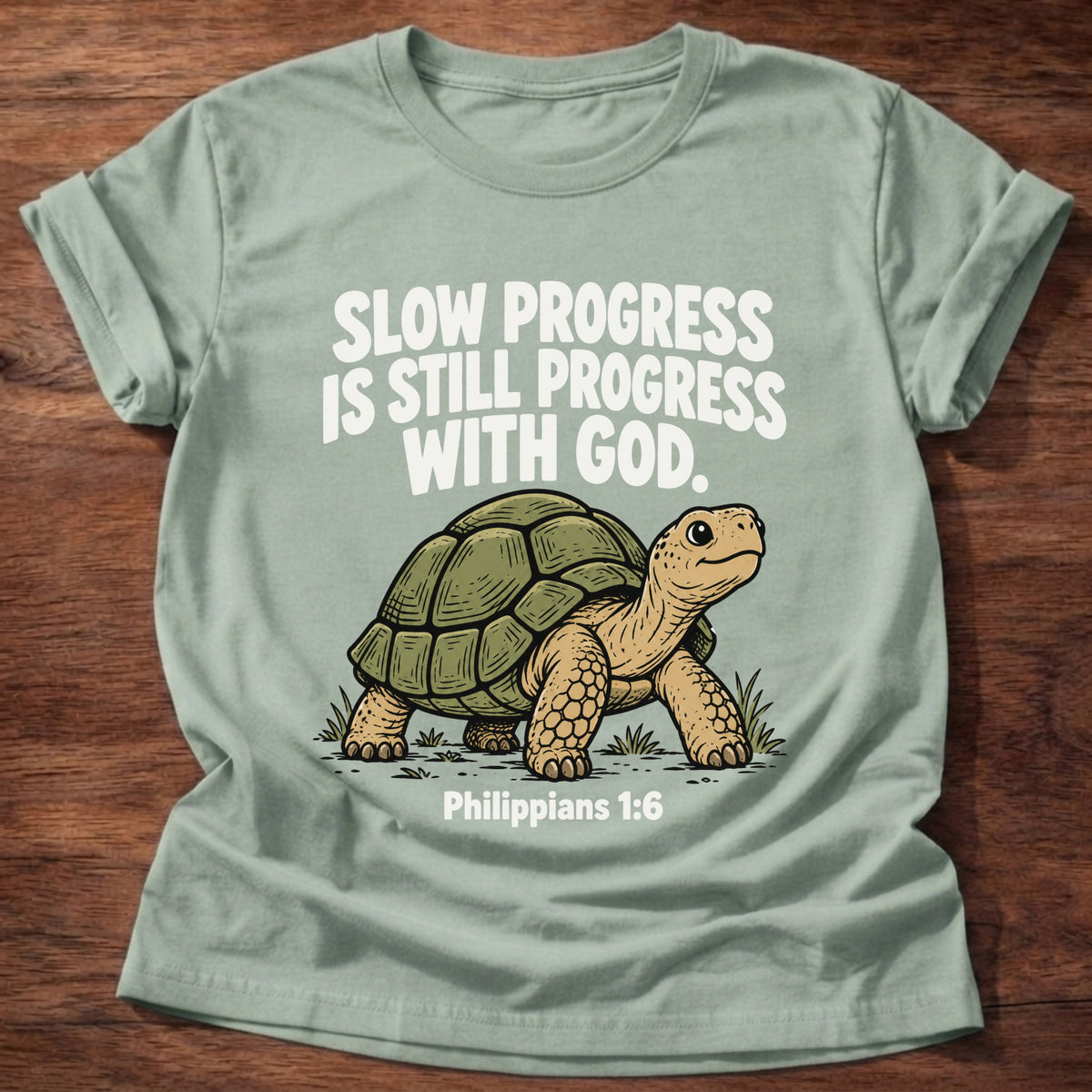 Sage t-shirt printed with a turtle graphic and 'Slow progress is still progress with God.' Philippians 1:6 faith based gift