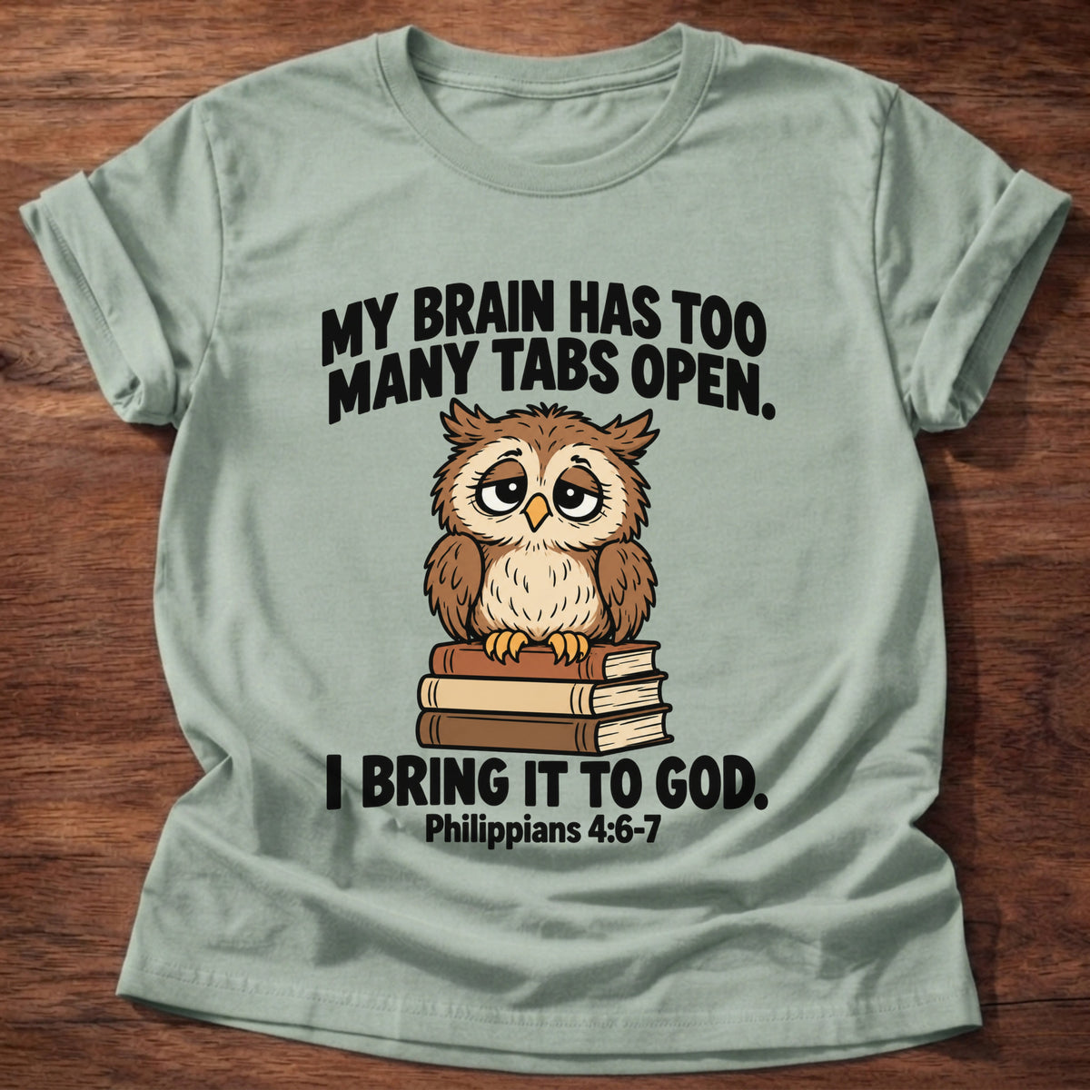 Sage t-shirt printed with an owl surrounded by books graphic and 'My brain has too many tabs open. I bring it to God.' Philippians 4:6-7 faith based gift