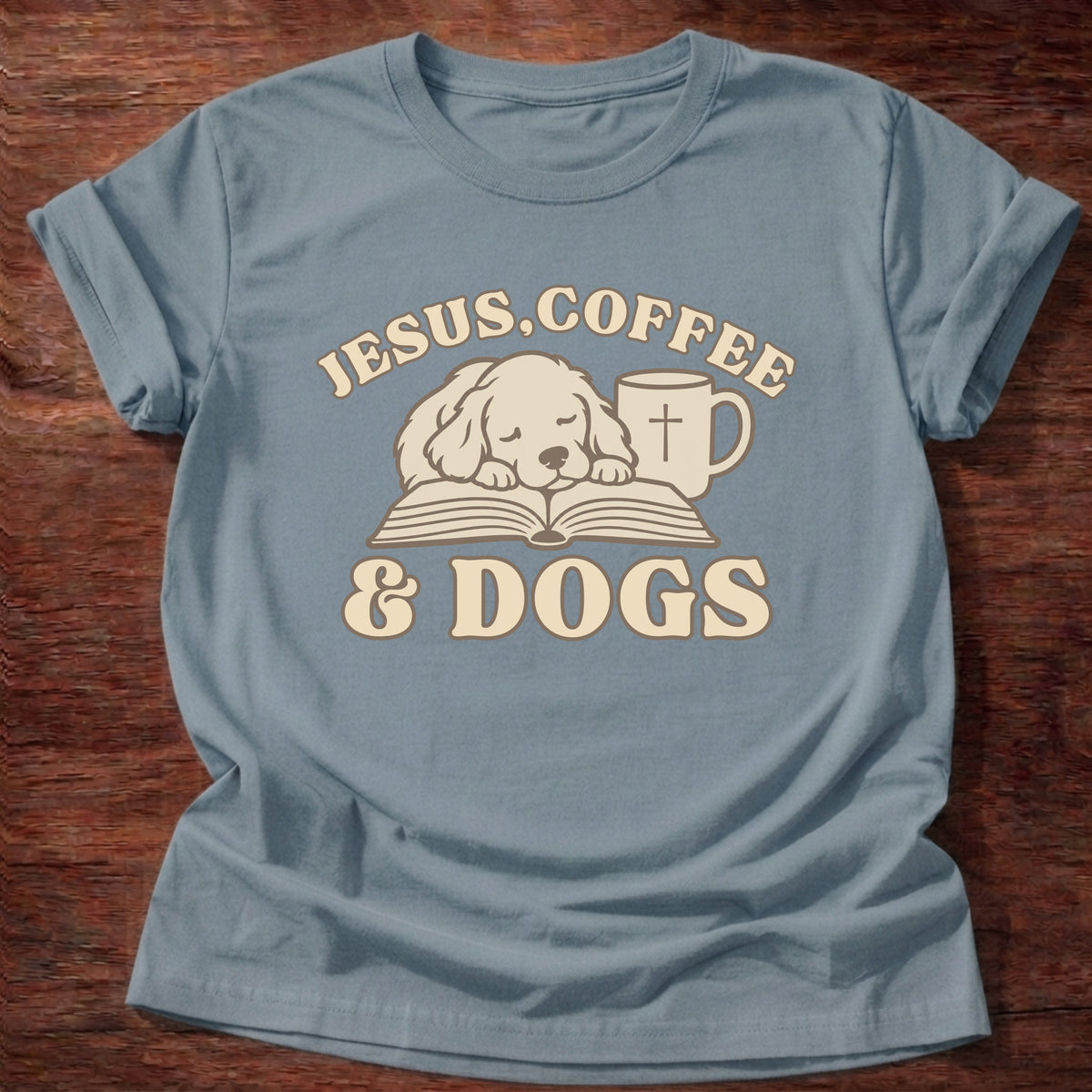 Stone Blue t-shirt printed with a sleepy puppy resting on an open Bible beside a coffee mug with a cross and “Jesus, Coffee & Dogs” Christian shirt