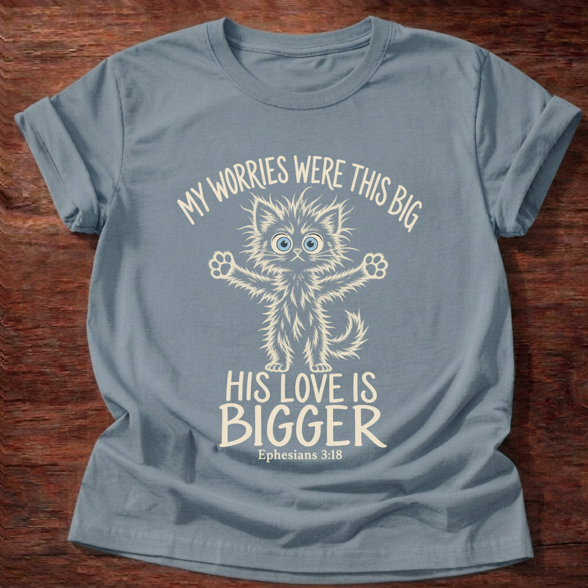Stone Blue t-shirt printed with a wide-eyed fluffy kitten stretching its arms wide graphic and “My worries were this big. His love is bigger.” Ephesians 3:18 Christian shirt