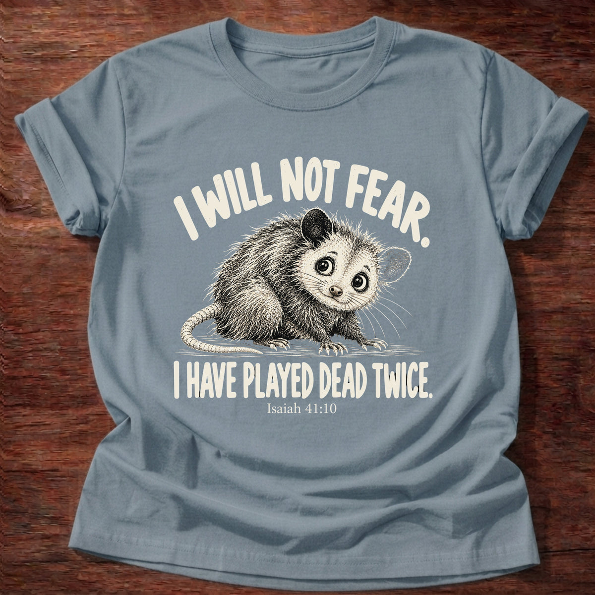 Stone Blue t-shirt printed with a wide-eyed opossum graphic and “I will not fear. I have played dead twice.” Isaiah 41:10 Christian shirt