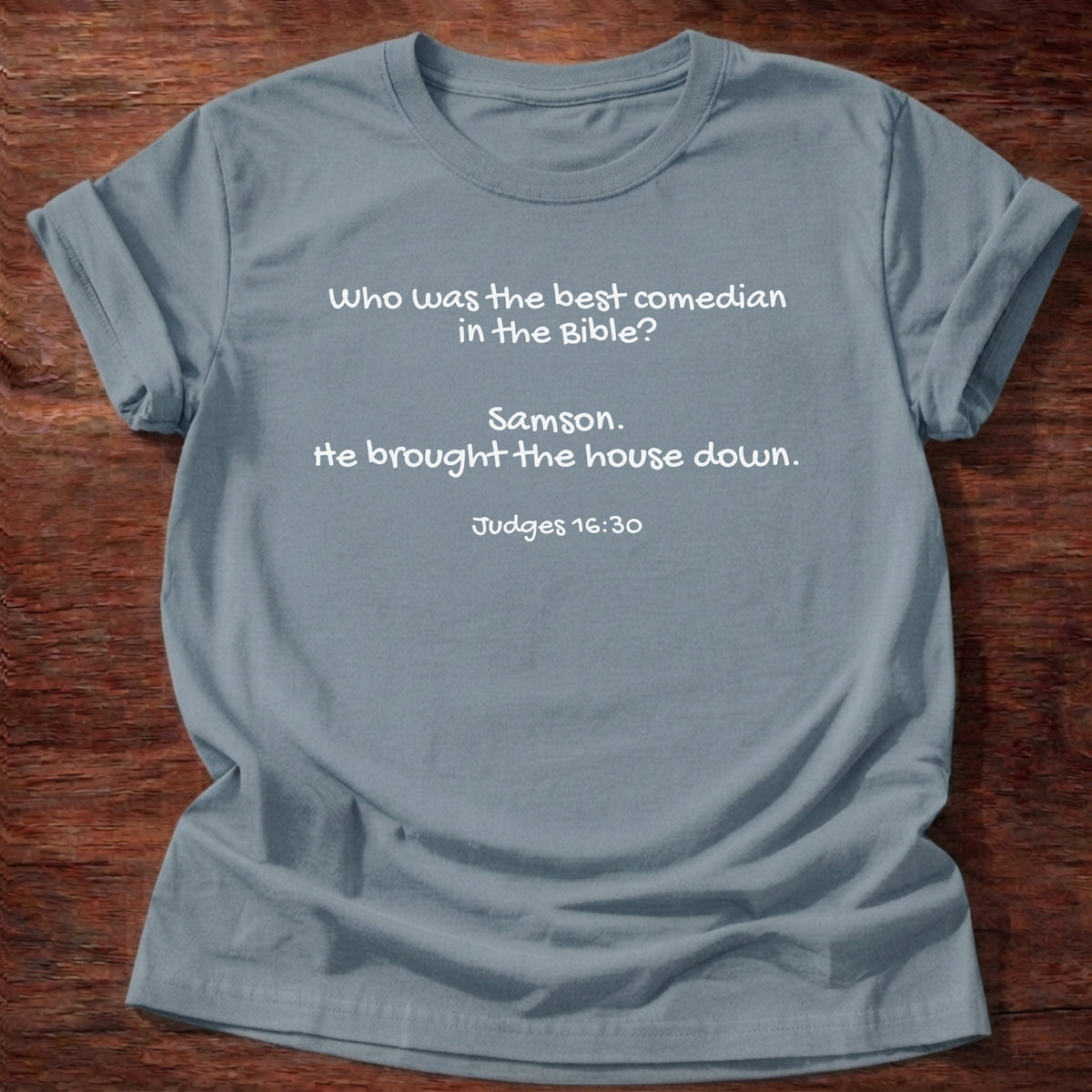 Stone Blue t-shirt printed with a simple hand-lettered Bible joke graphic and “Who was the best comedian in the Bible? Samson. He brought the house down.” Judges 16:30 Christian shirt