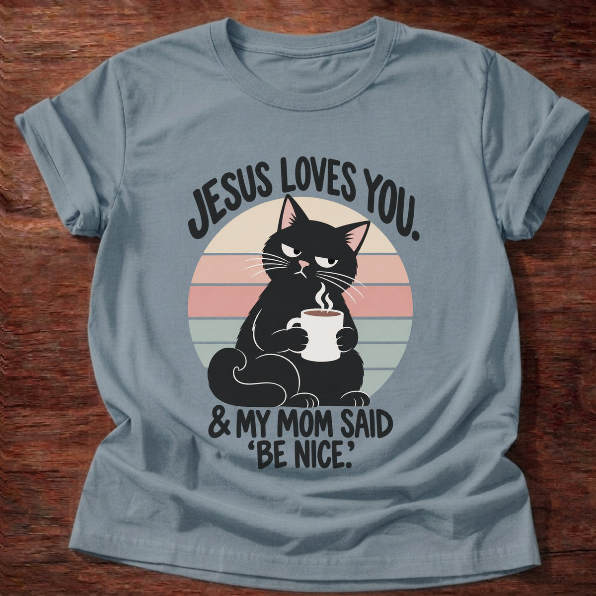 Stone Blue t-shirt printed with a grumpy black cat holding a steaming coffee mug in front of a retro striped sunset graphic and “Jesus loves you. & my mom said 'be nice.'” faith based gift