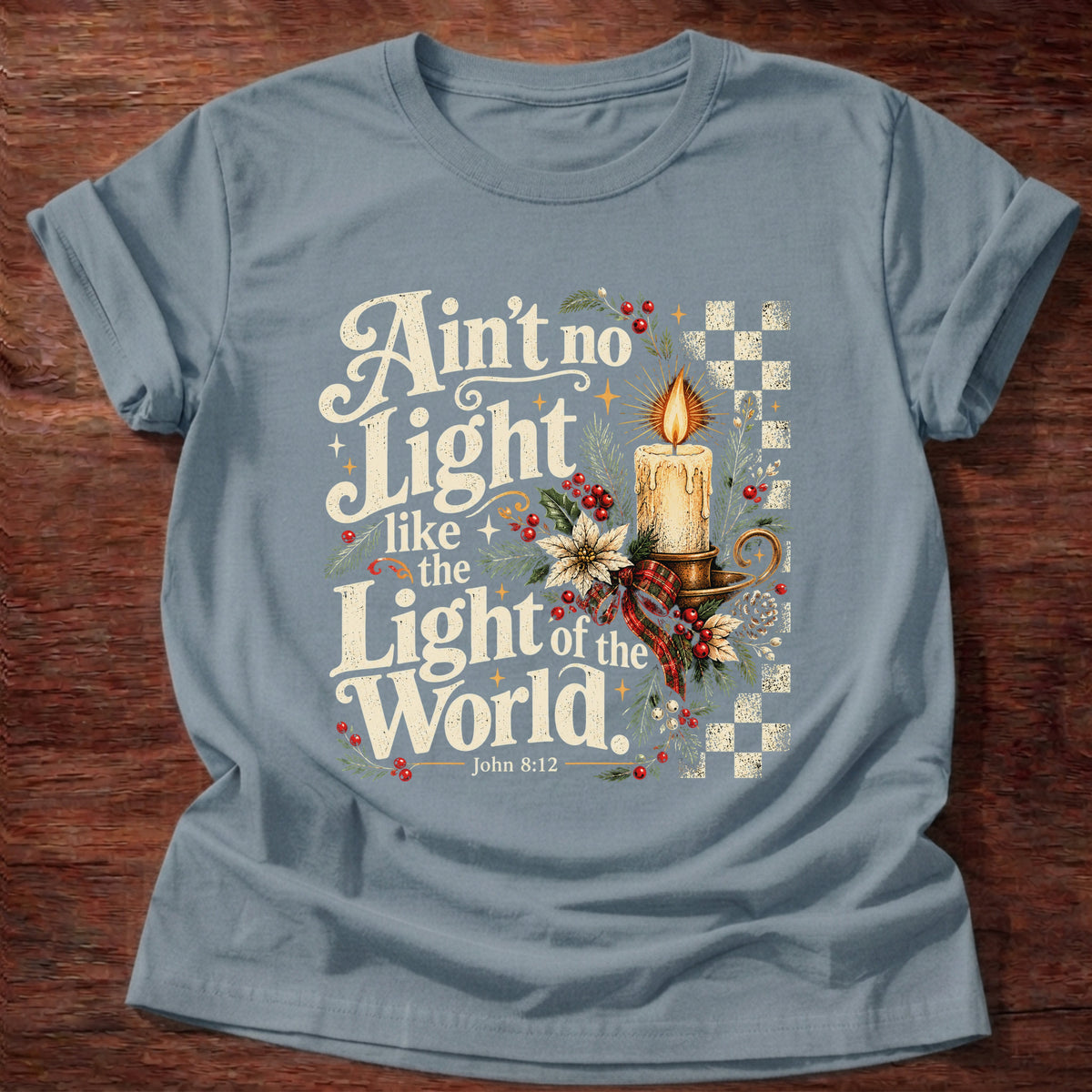 Stone Blue t-shirt printed with a retro glowing candle with poinsettias and checkerboard graphic and “Ain't no light like the Light of the World.” John 8:12 Christian shirt