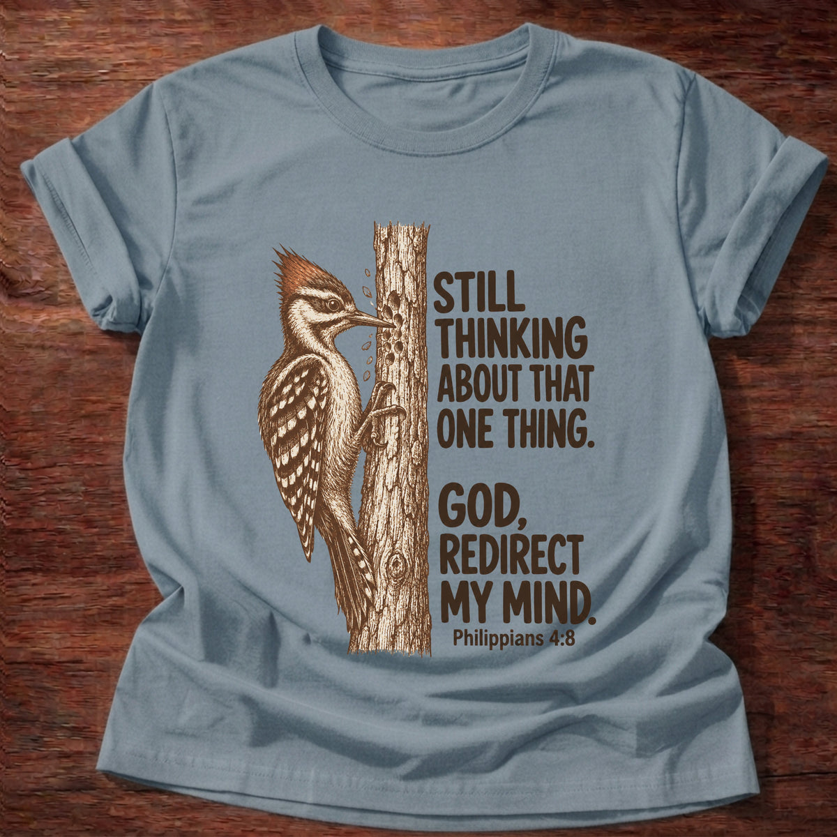 Stone Blue t-shirt printed with a woodpecker pecking at a tree trunk graphic and “Still thinking about that one thing. God, redirect my mind.” Philippians 4:8 faith based gift