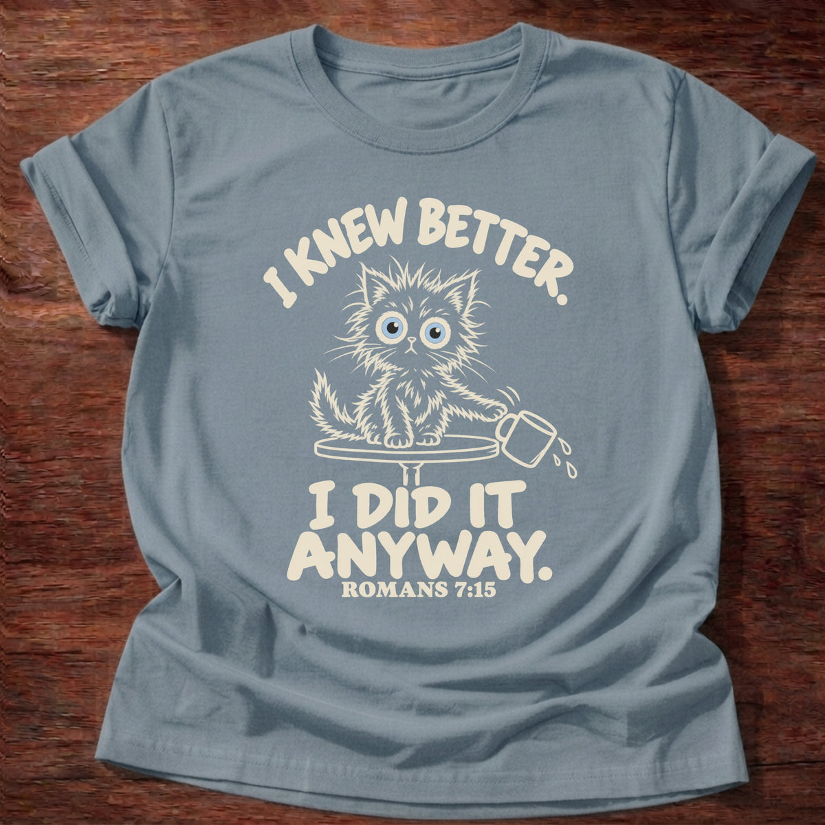 Stone Blue t-shirt printed with a scruffy kitten knocking a cup off a table and “I knew better. I did it anyway.” Romans 7:15 Christian shirt