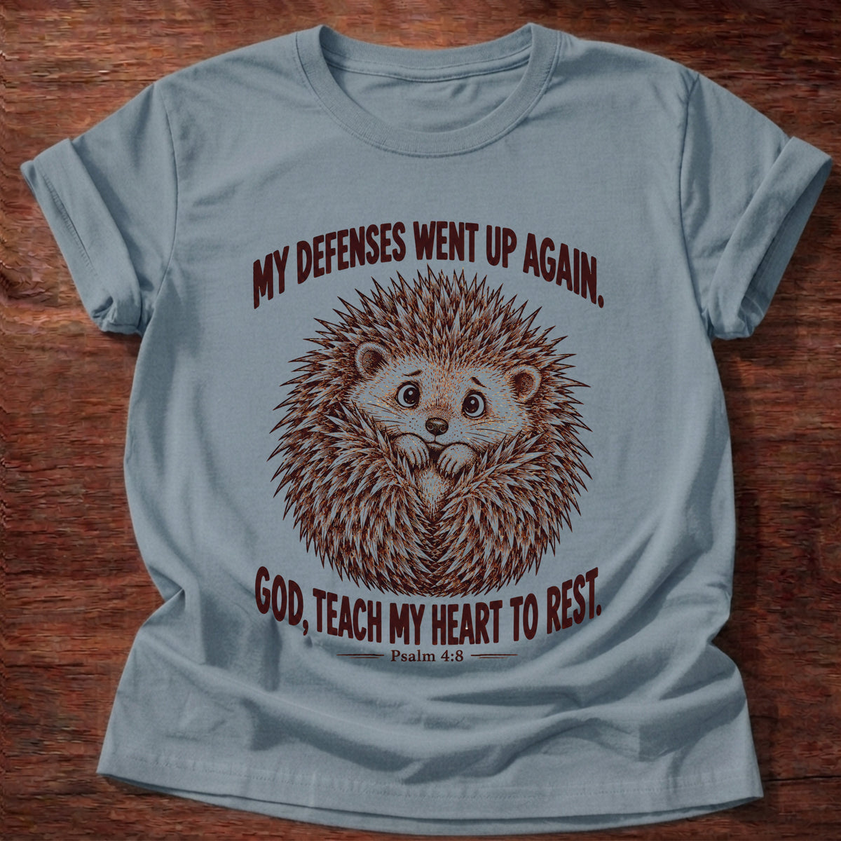 Stone Blue t-shirt printed with a worried hedgehog curled up with its quills raised graphic and “My defenses went up again. God, teach my heart to rest.” Psalm 4:8 faith based gift