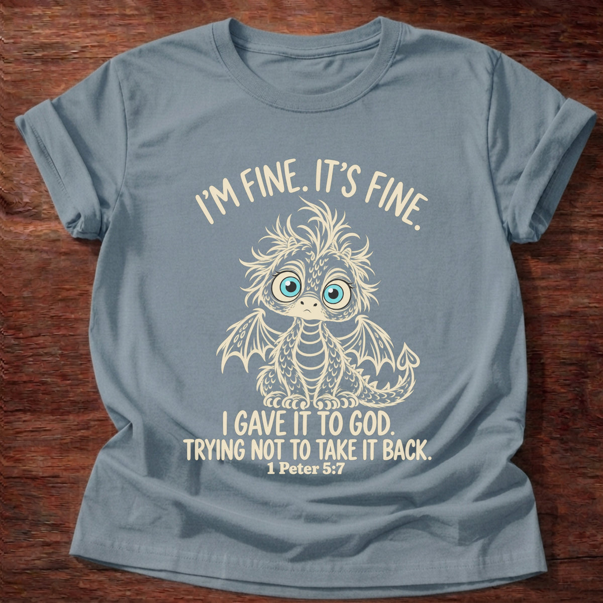 Stone Blue t-shirt printed with a wide-eyed, frazzled baby dragon graphic and “I'm fine. It's fine. I gave it to God. Trying not to take it back.” 1 Peter 5:7 Christian shirt